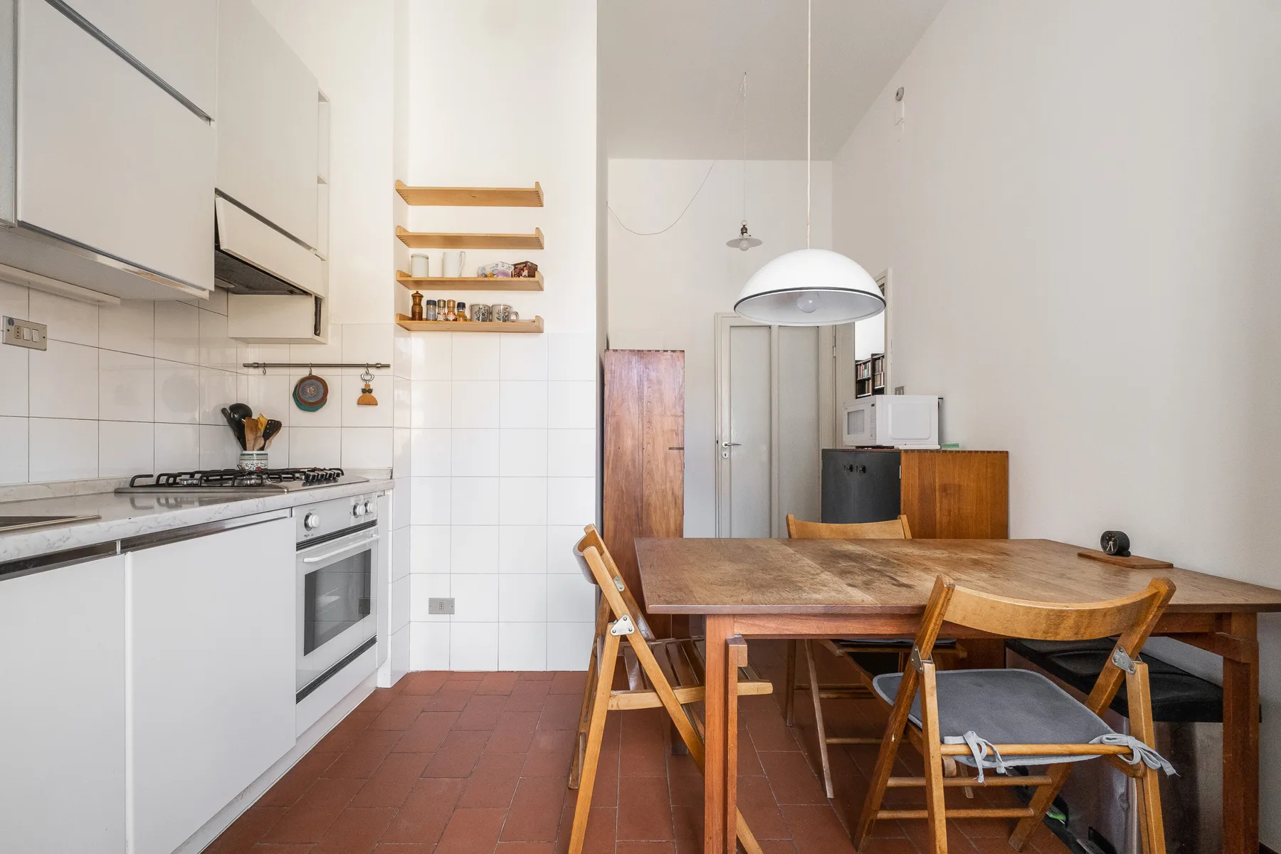 A kitchen and dining area with a wooden table and white cabinets.