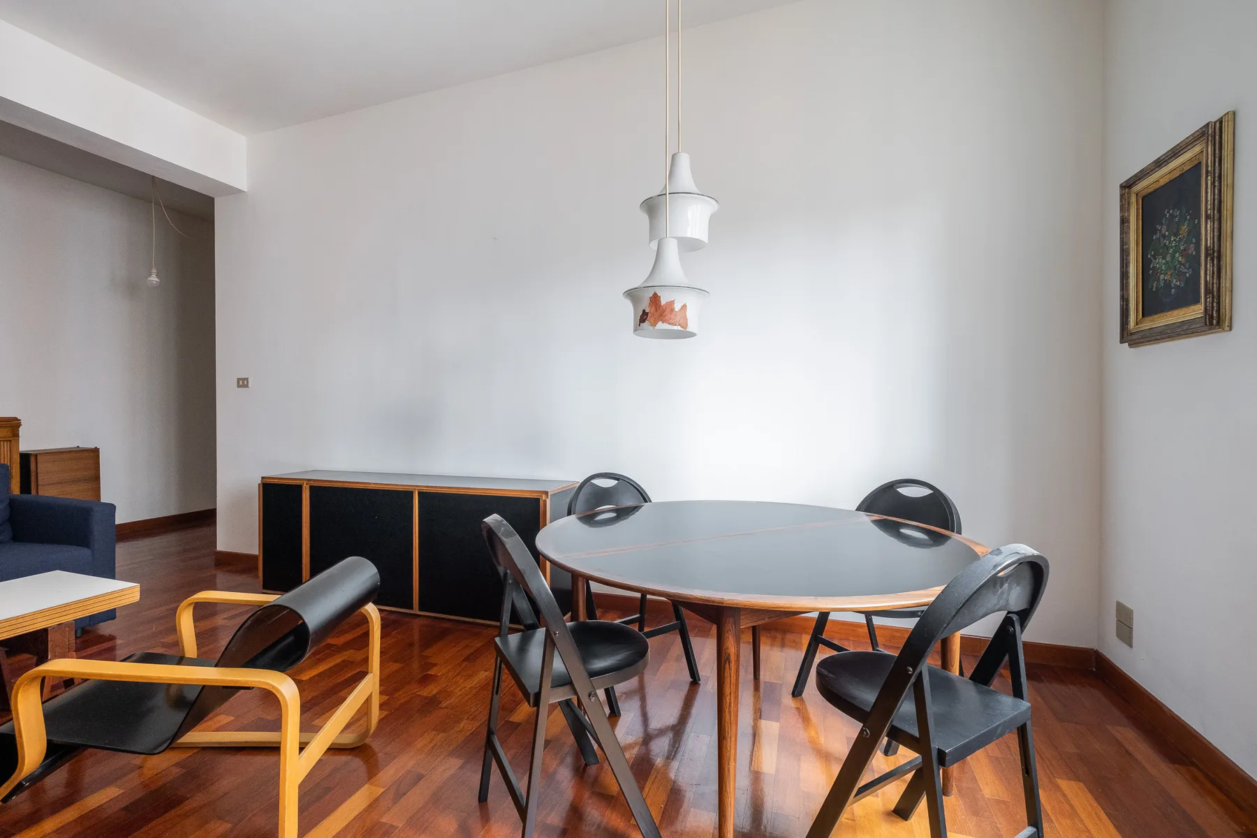 A dining area with a round table, chairs, and a pendant light.