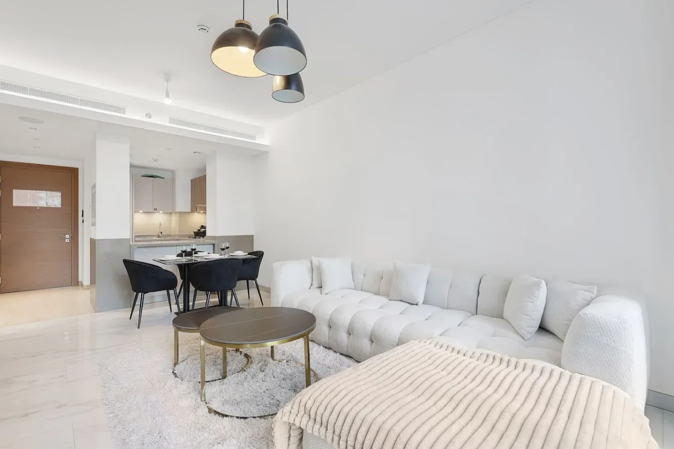 Una luminosa sala de estar y comedor con asientos blancos y una mesa.