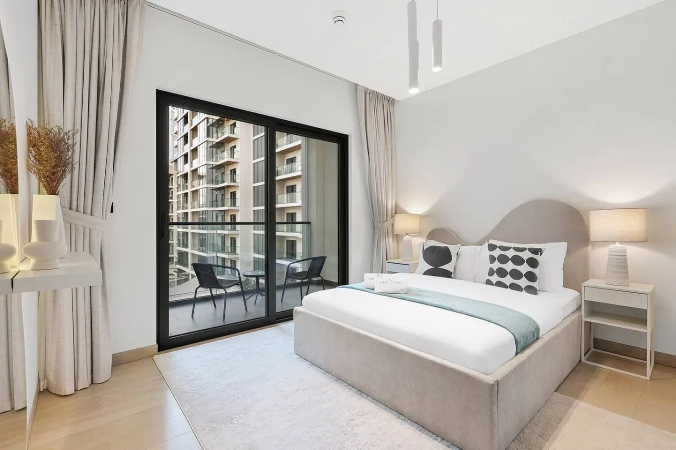 Un dormitorio luminoso con una cama grande y puertas corredizas de vidrio que dan a un balcón.