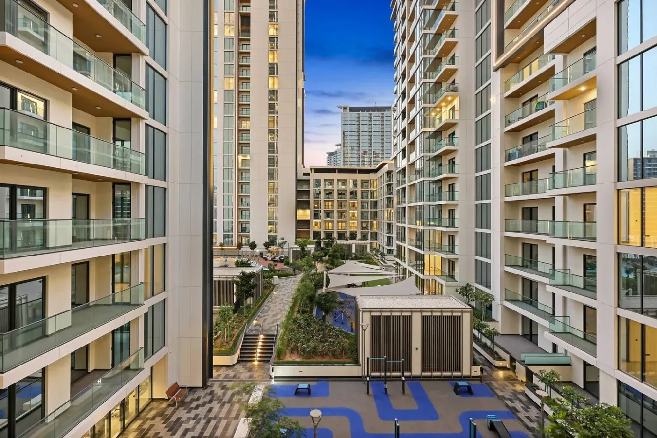Un patio entre edificios de apartamentos modernos, con balcones y senderos ajardinados.