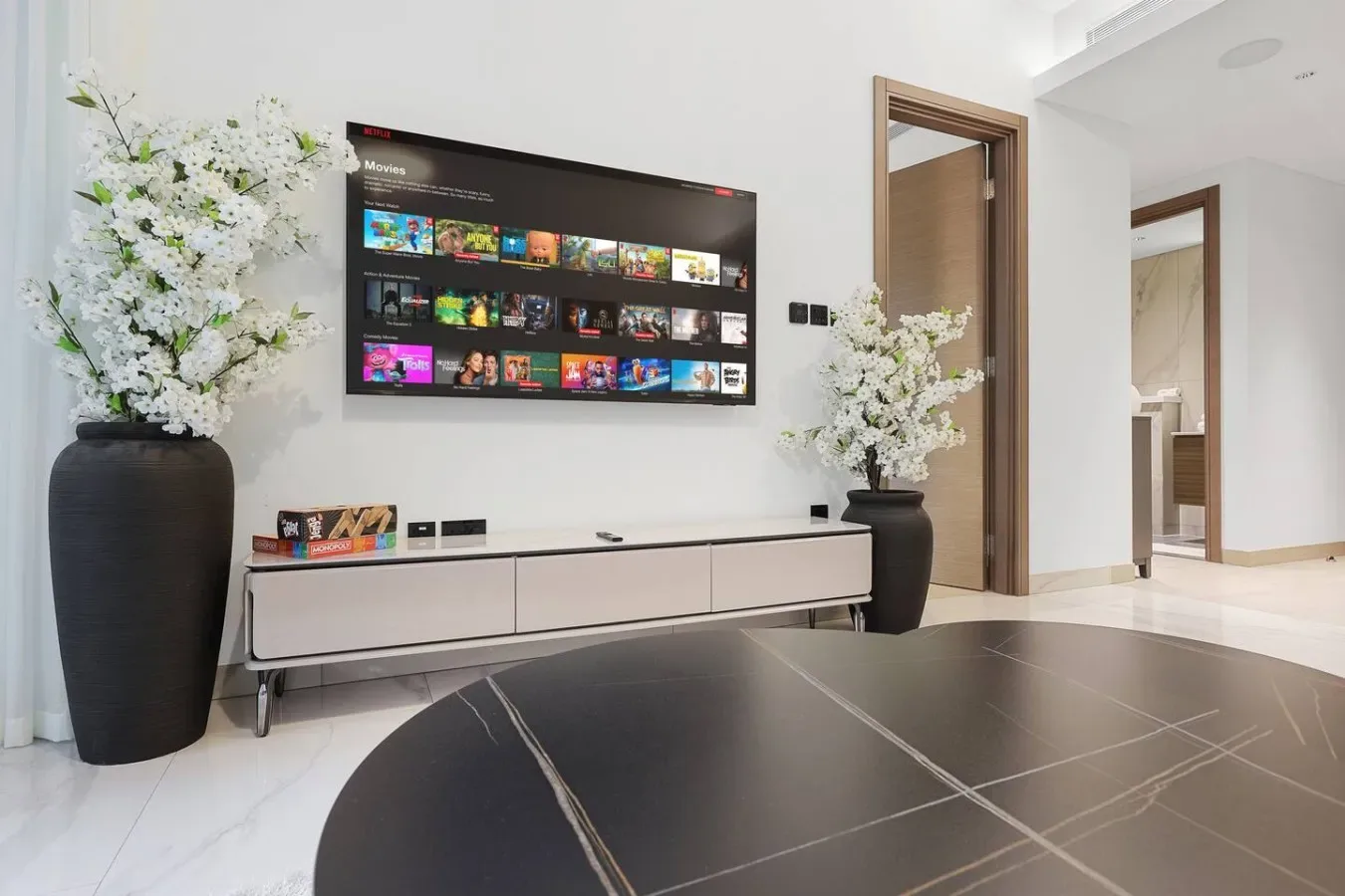Una sala de estar con un televisor en la pared sobre un mueble bajo.