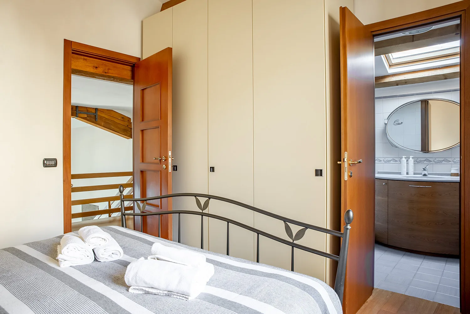 Un dormitorio con ropa de cama a rayas y puertas abiertas hacia un baño.