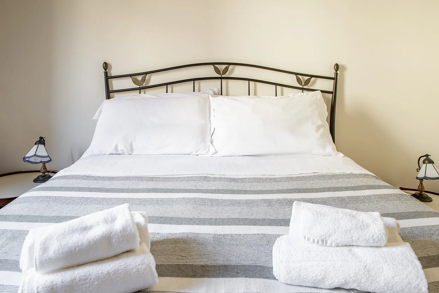 Un dormitorio con una cama bien hecha y toallas blancas dobladas.