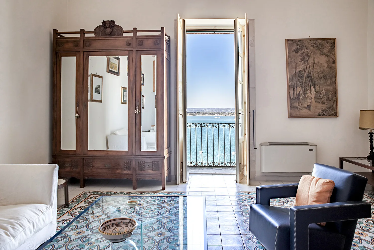 Una sala de estar con una puerta alta abierta y vistas al mar.