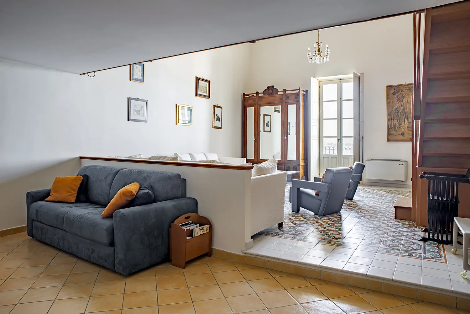 Una sala de estar con un sofá oscuro y asientos junto a ventanas altas.