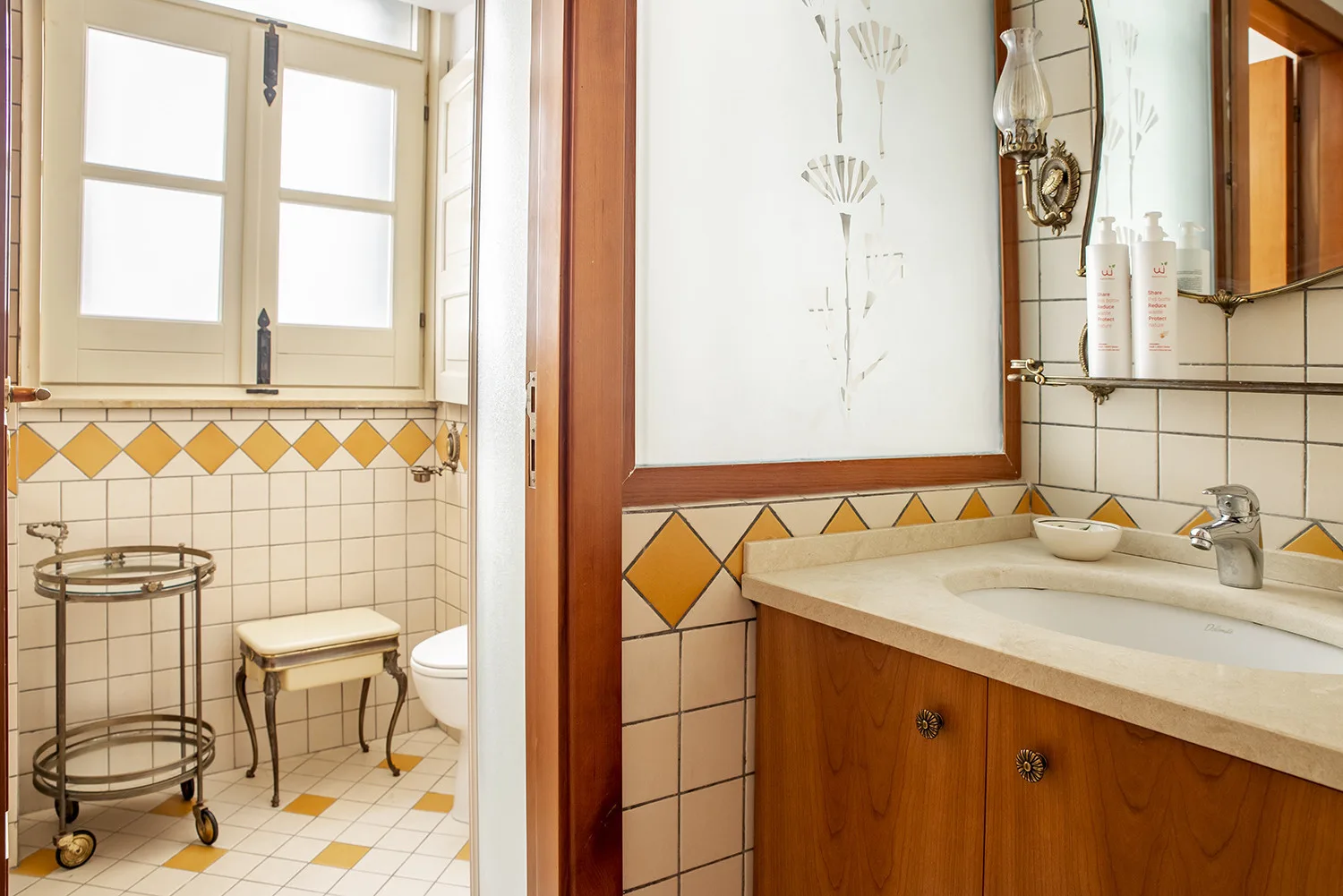 Un baño alicatado con lavabo, ventana e inodoro.