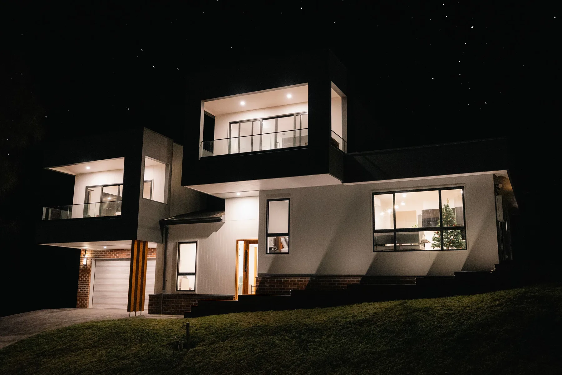 Exterior de una casa moderna de noche, con ventanas iluminadas.