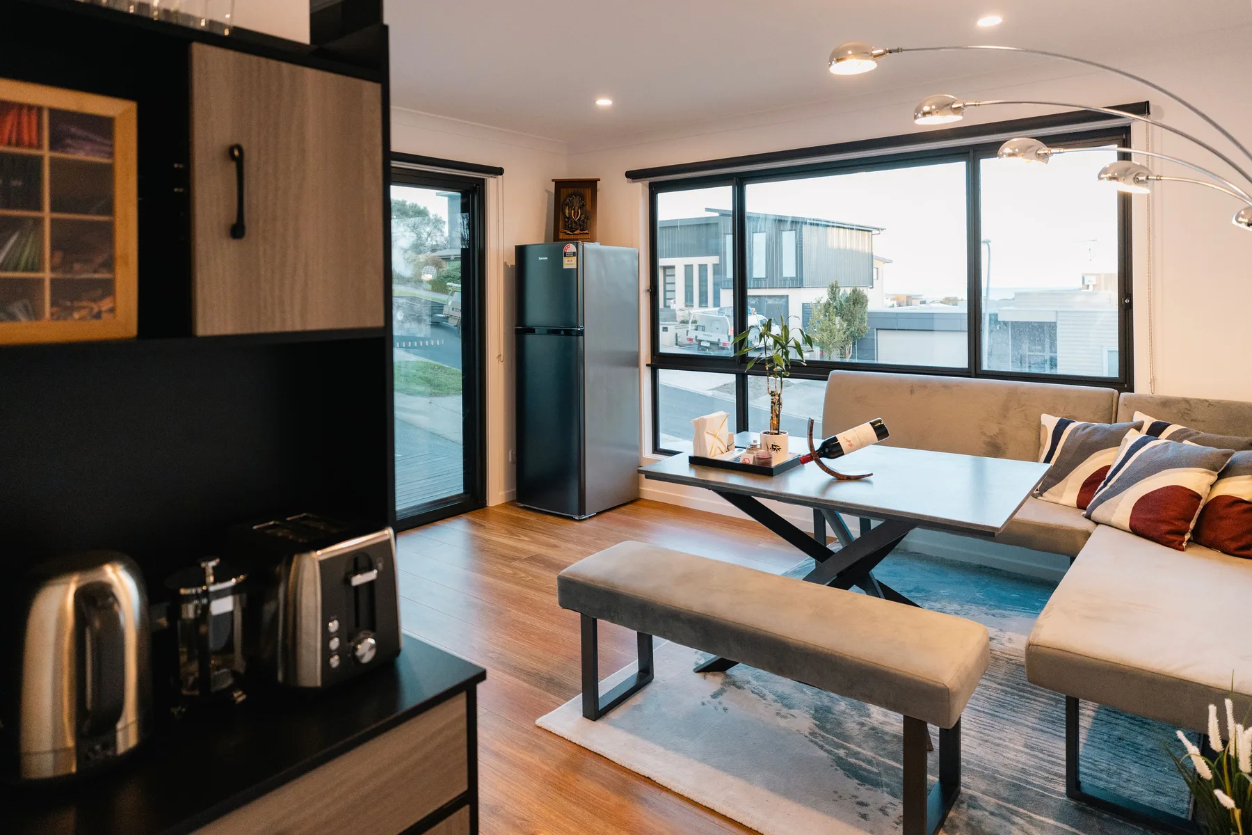Una luminosa sala de estar con mesa de comedor y asientos junto a grandes ventanas.