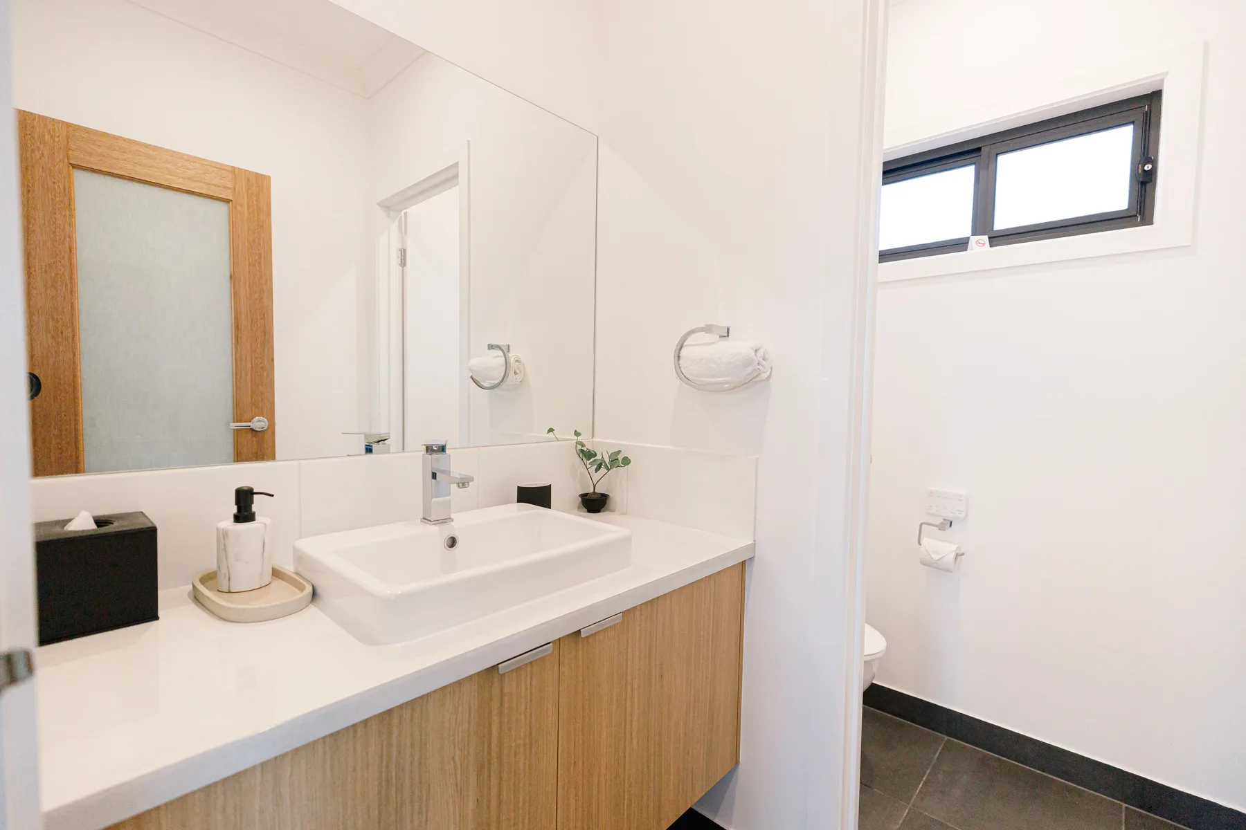 Un baño luminoso con un amplio lavabo y una ventana pequeña.
