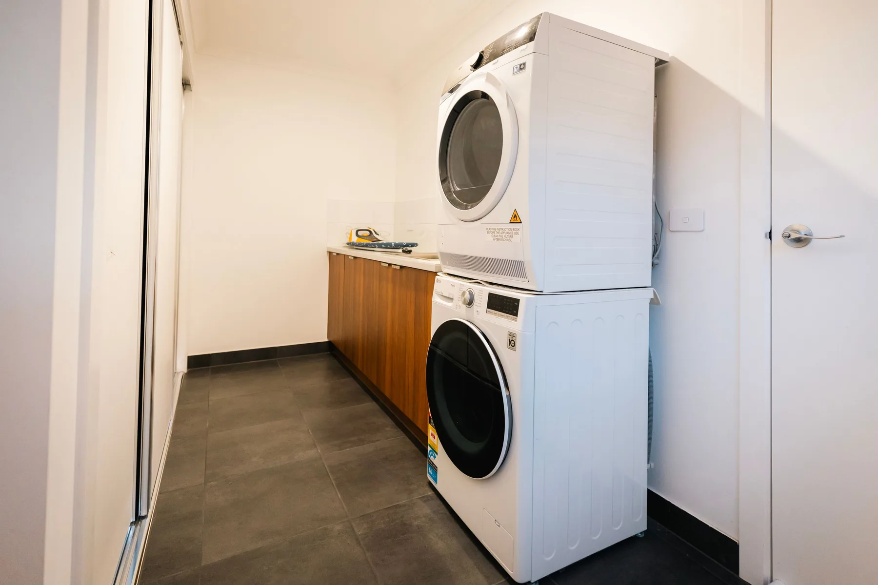 Un cuarto de lavandería con lavadora y secadora apiladas junto a una encimera de madera.