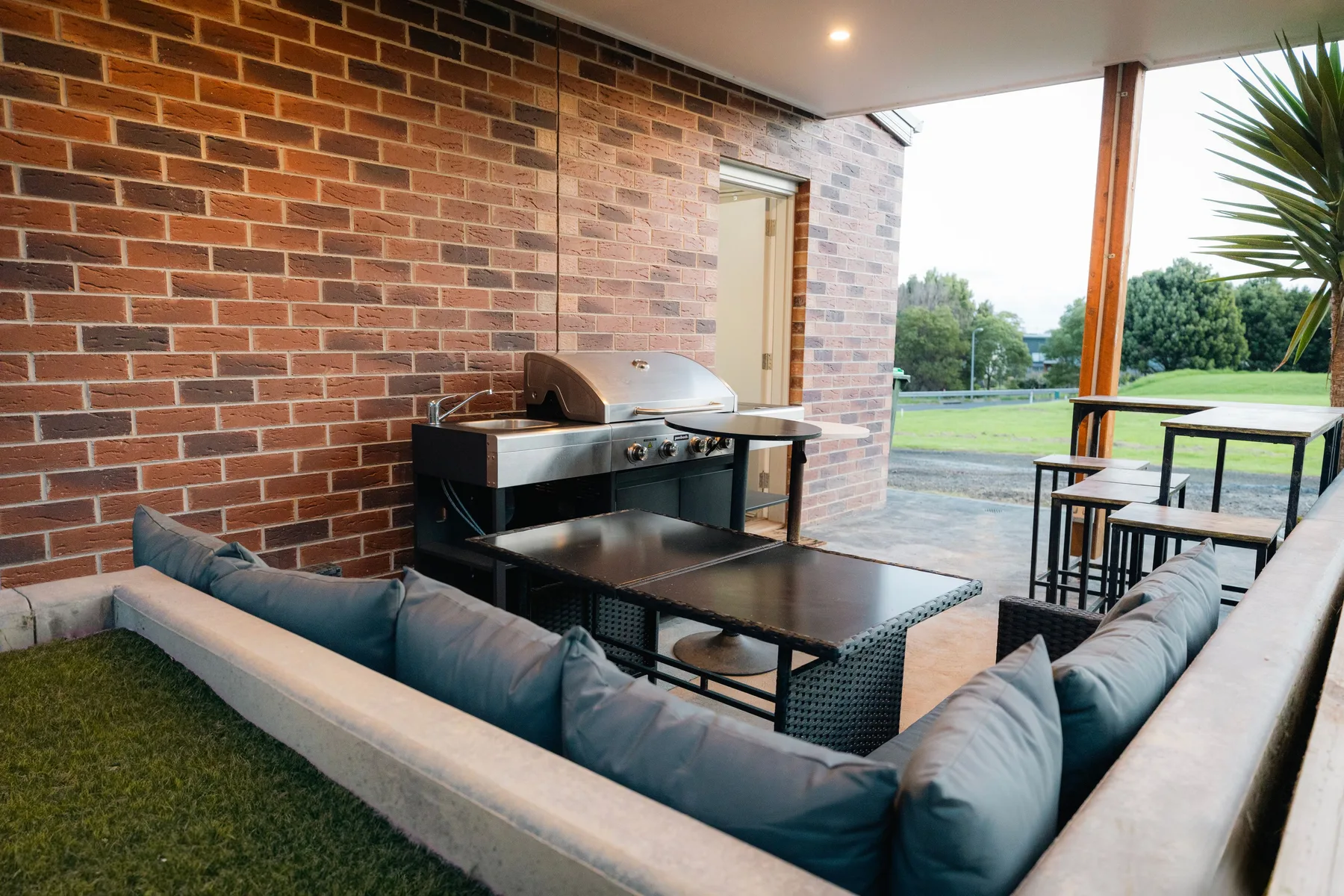 Un patio cubierto con asientos al aire libre y una barbacoa junto a una pared de ladrillo.