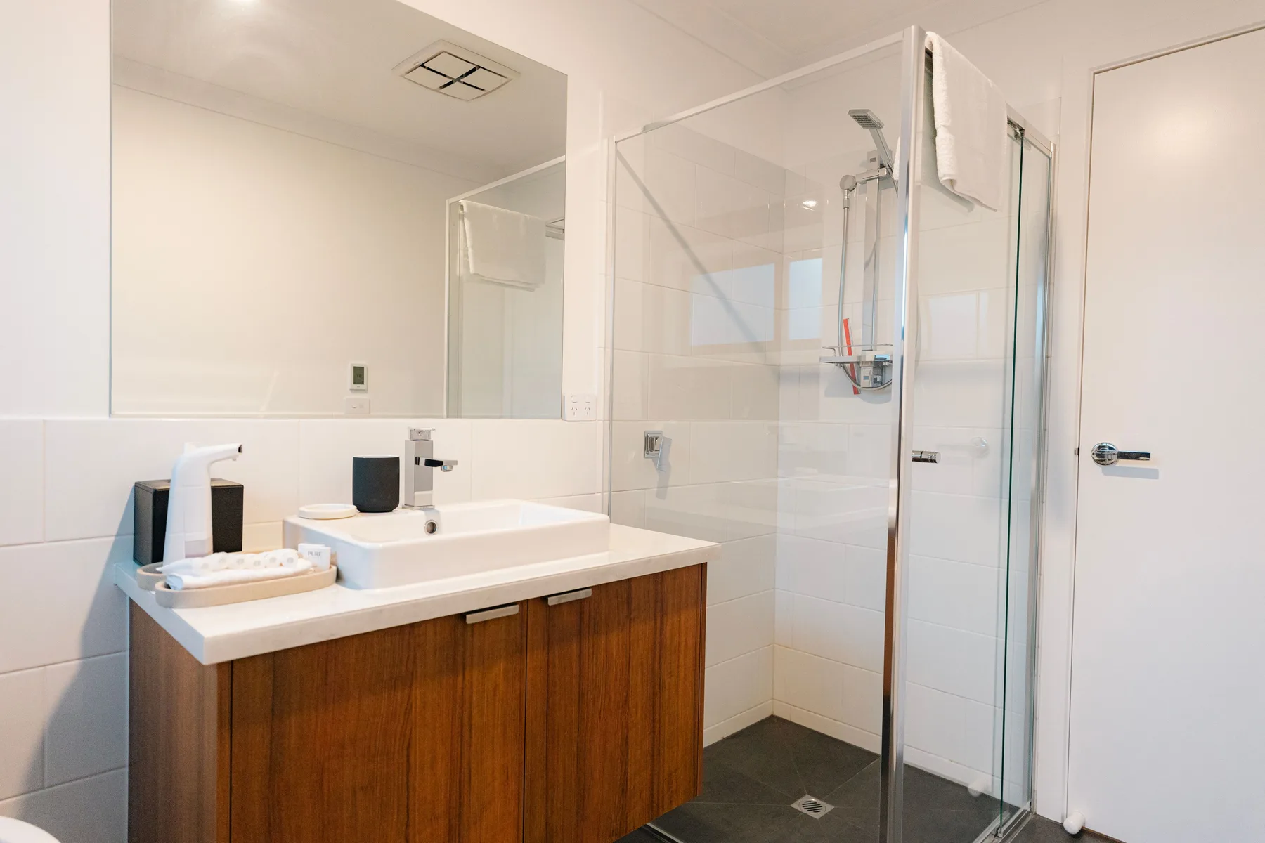 Un baño luminoso con lavabo y ducha de cristal.