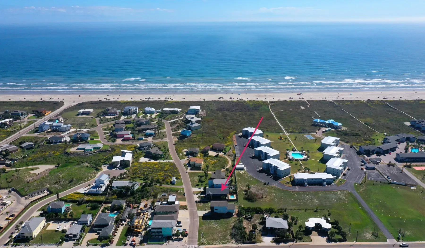 Vista aérea de viviendas costeras junto a una playa de arena y el océano.