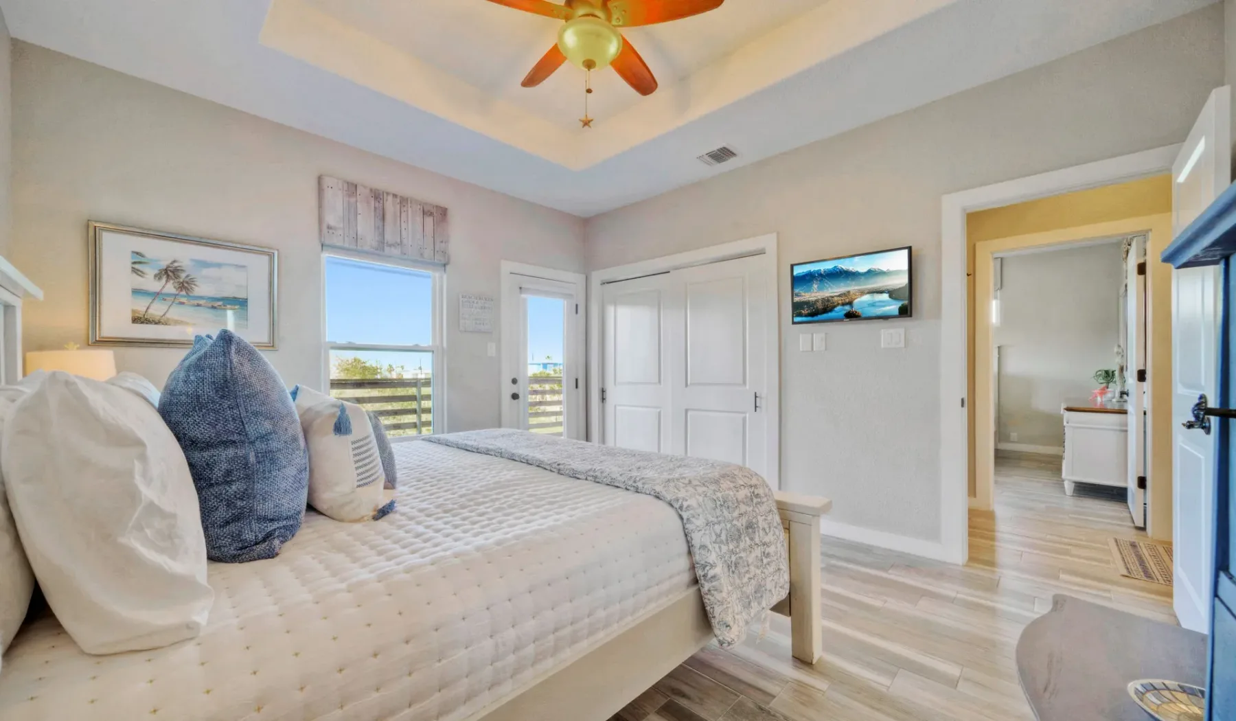 Un dormitorio luminoso con cama, ventanas y ventilador de techo.