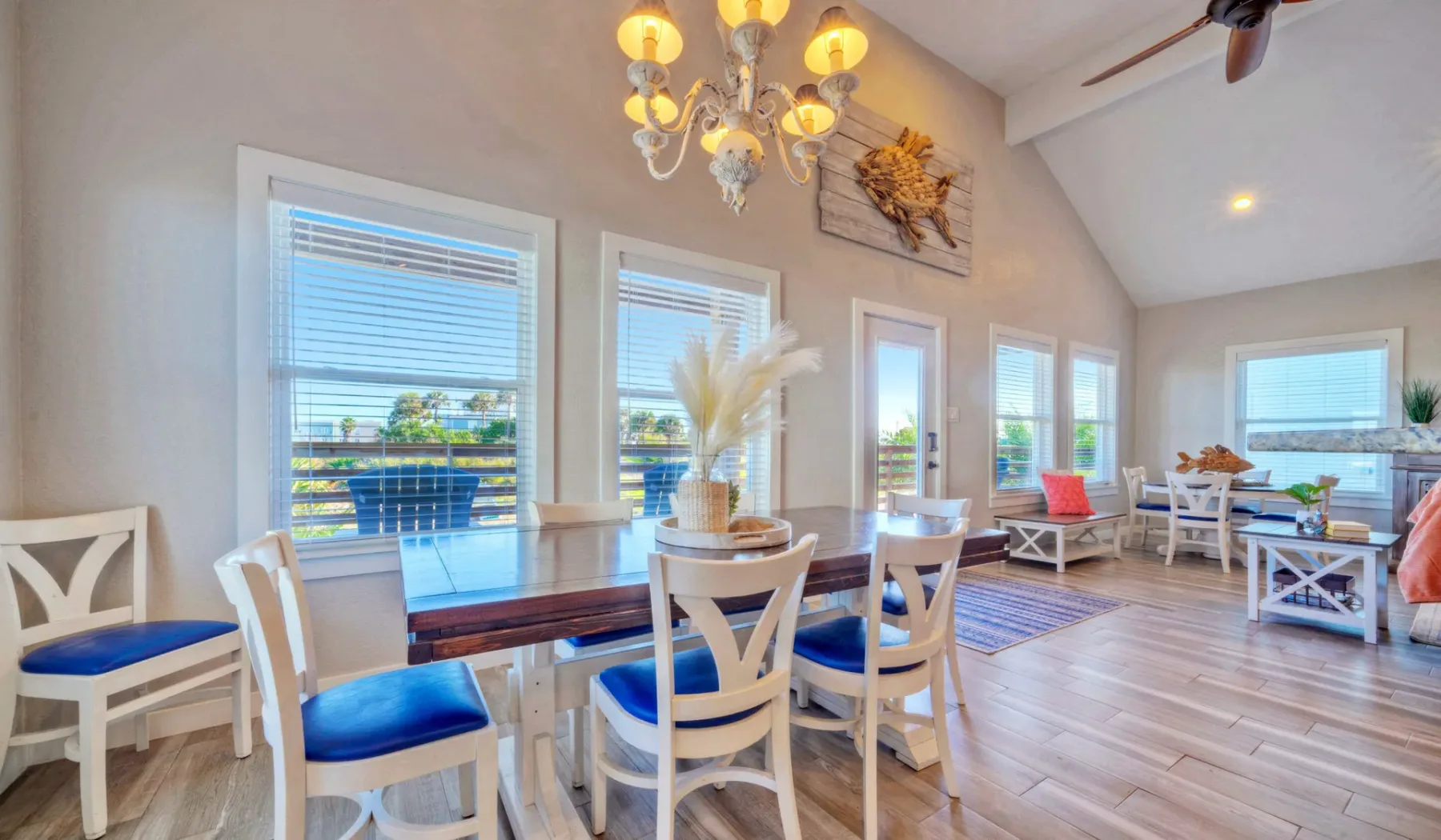 Una luminosa zona de comedor y estar con grandes ventanas y una mesa de madera.
