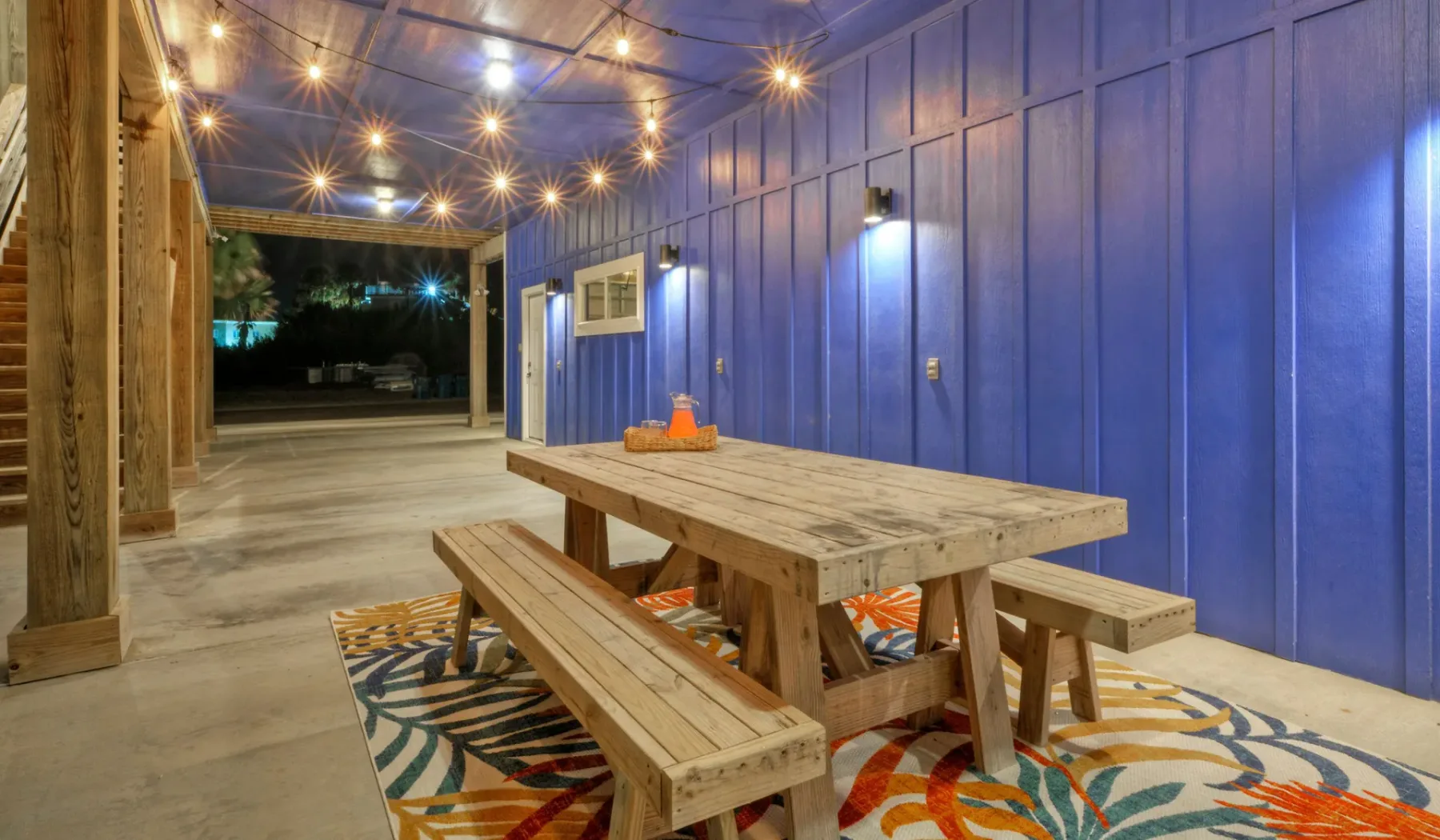 Un comedor exterior cubierto con una mesa de picnic de madera y luces colgantes.