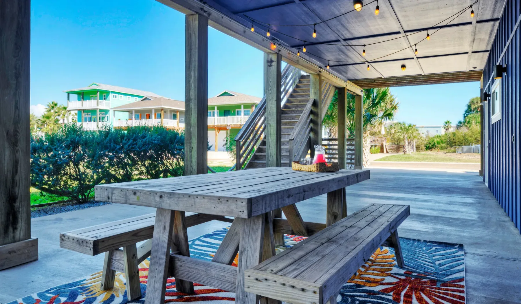 Una zona exterior cubierta con una mesa de picnic de madera y luces colgantes.