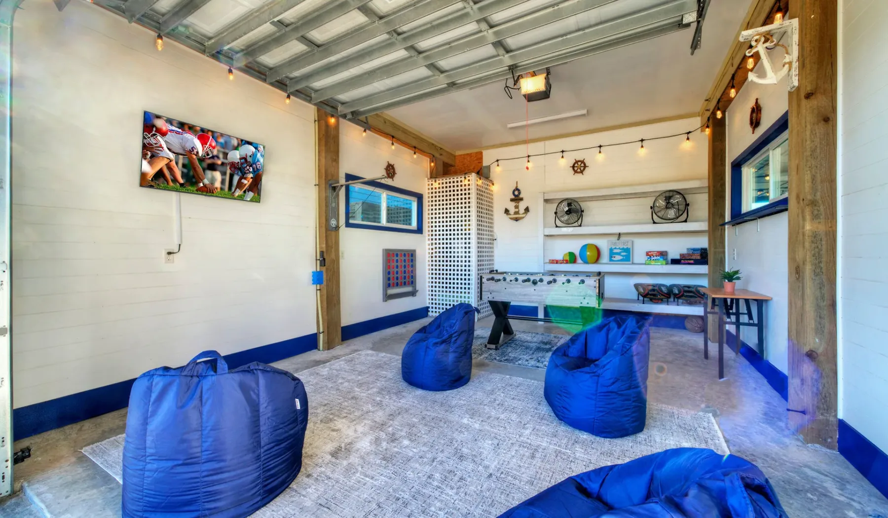 Una sala de juegos luminosa con asientos tipo puf azules y una mesa de futbolín.