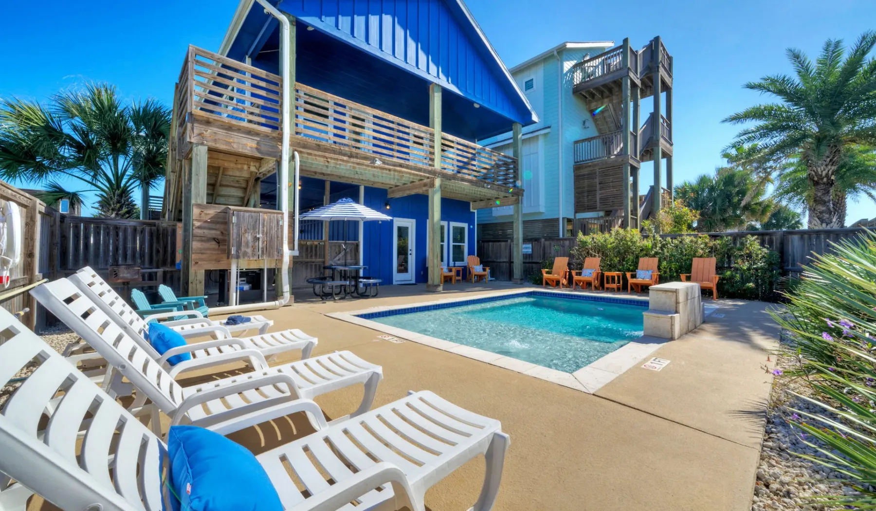 Una piscina y asientos de descanso están junto a una casa de playa azul.