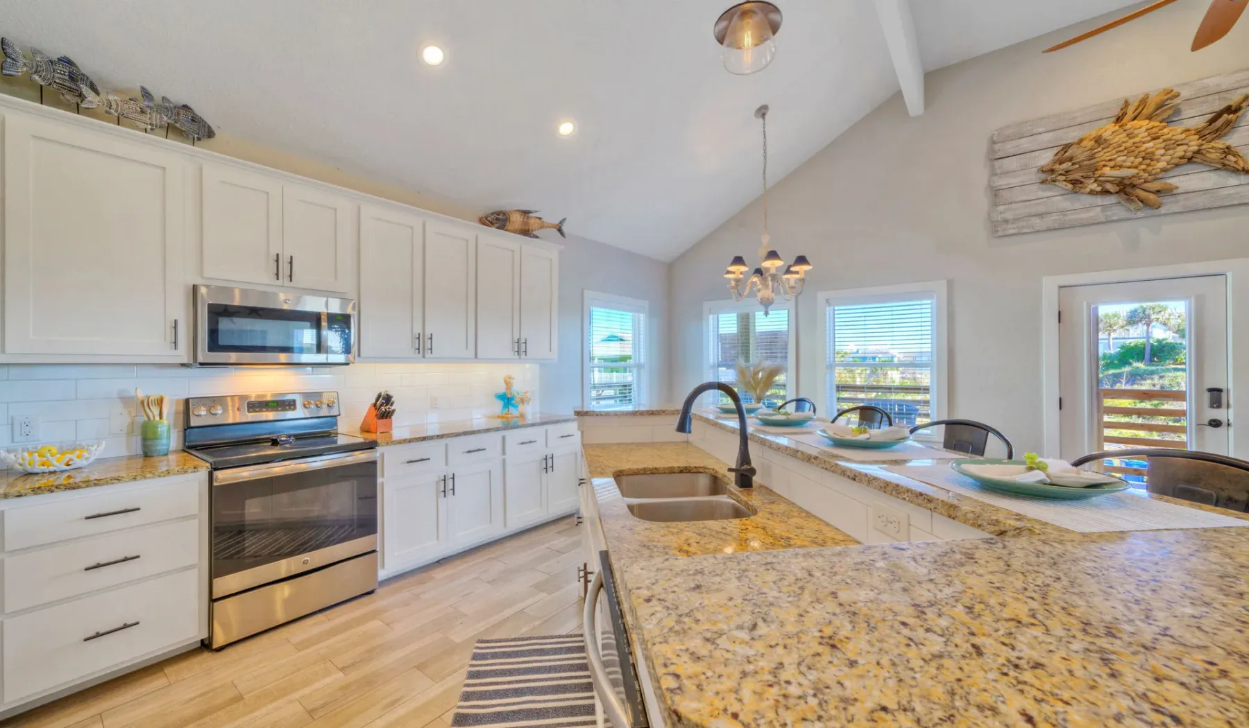 Una cocina luminosa con gabinetes blancos y una isla grande de piedra.