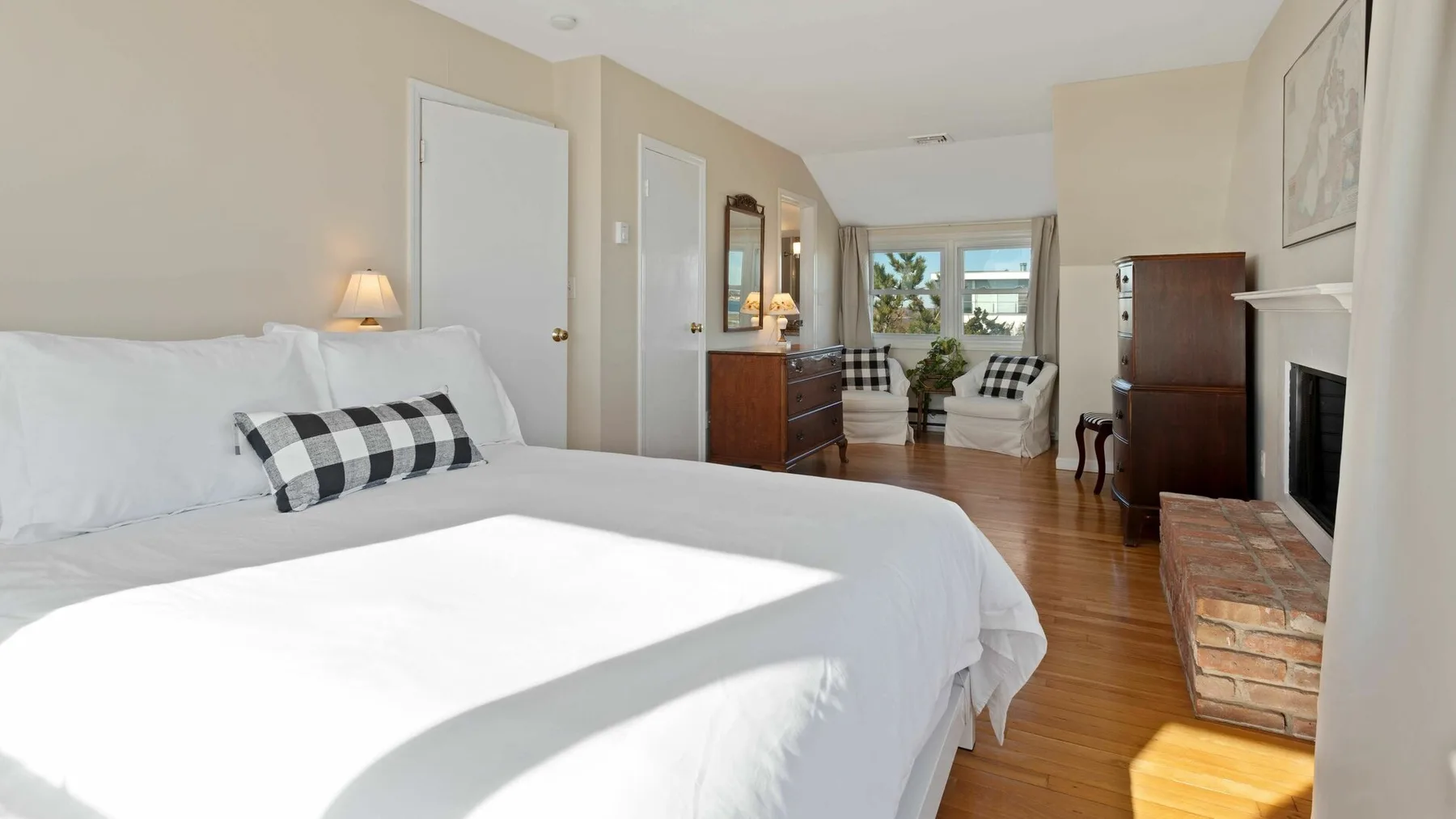 Un dormitorio luminoso con una cama grande y una zona de estar junto a las ventanas.
