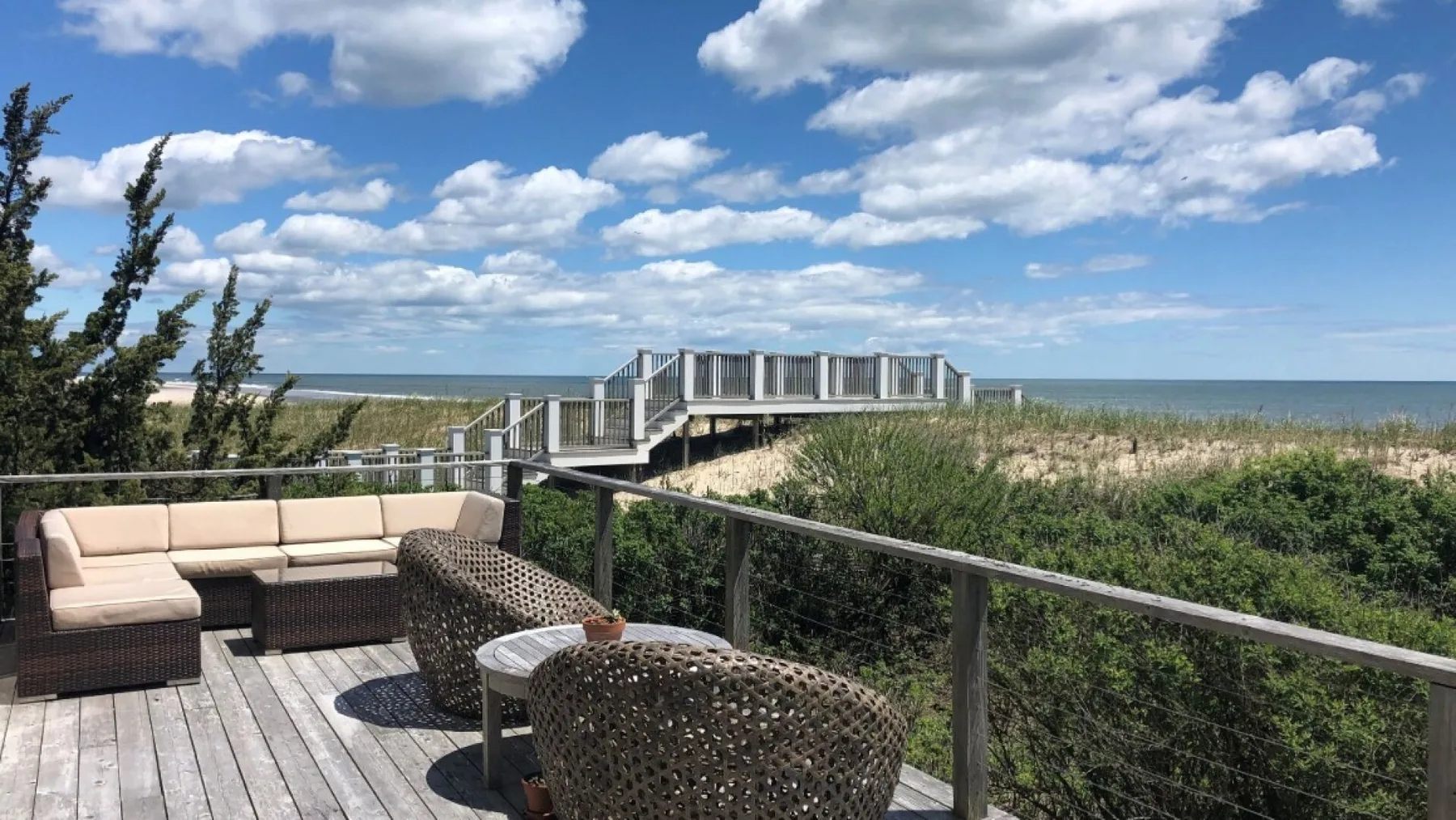 Una terraza con asientos al aire libre da a las dunas costeras y al océano.