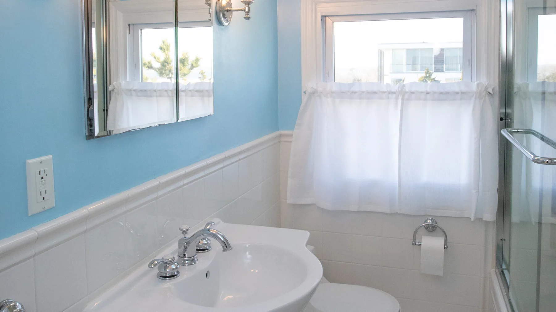 Un baño con lavabo, inodoro y ducha junto a una ventana.