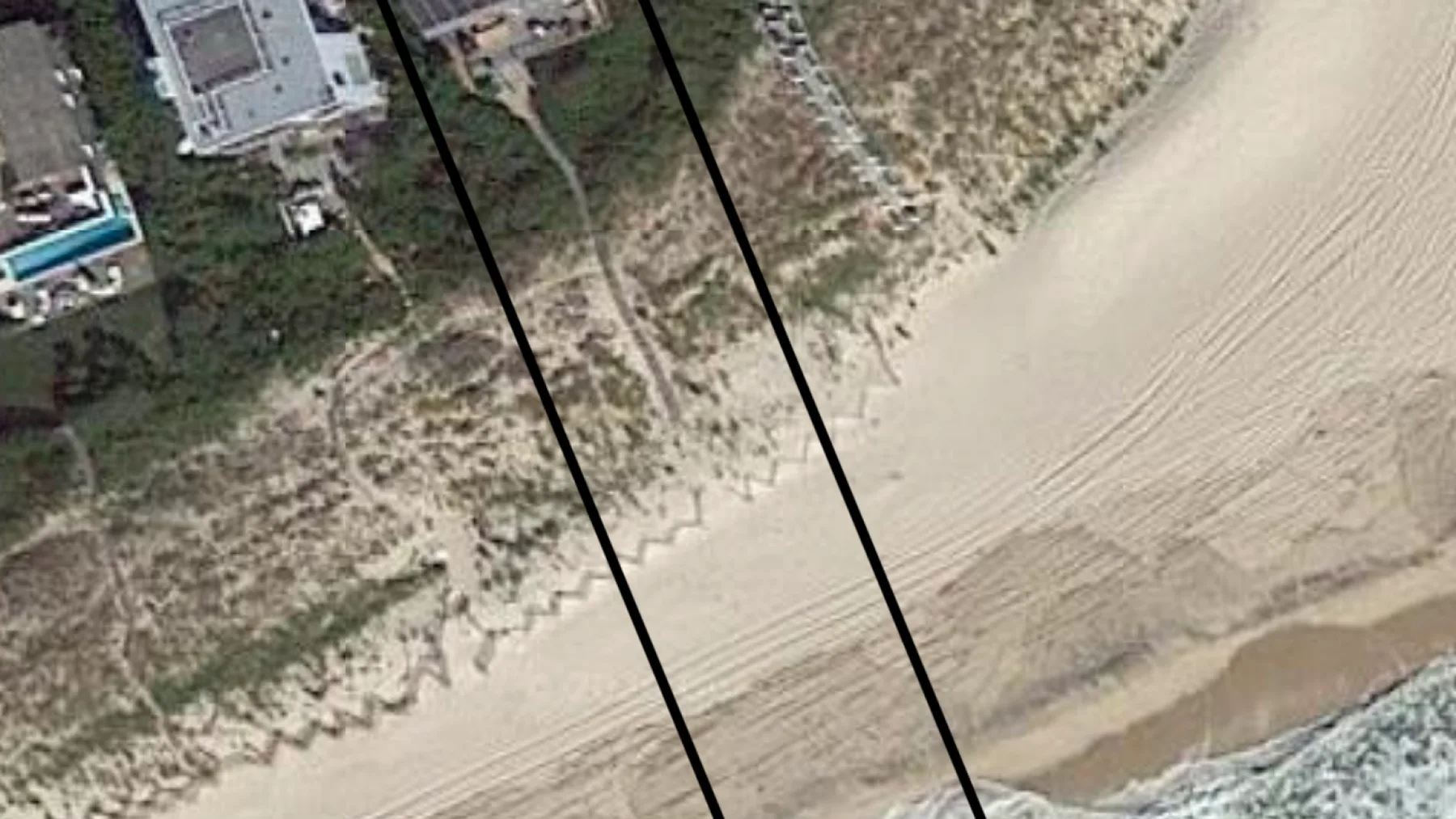 Una vista aérea muestra una playa de arena, dunas y edificios cercanos.