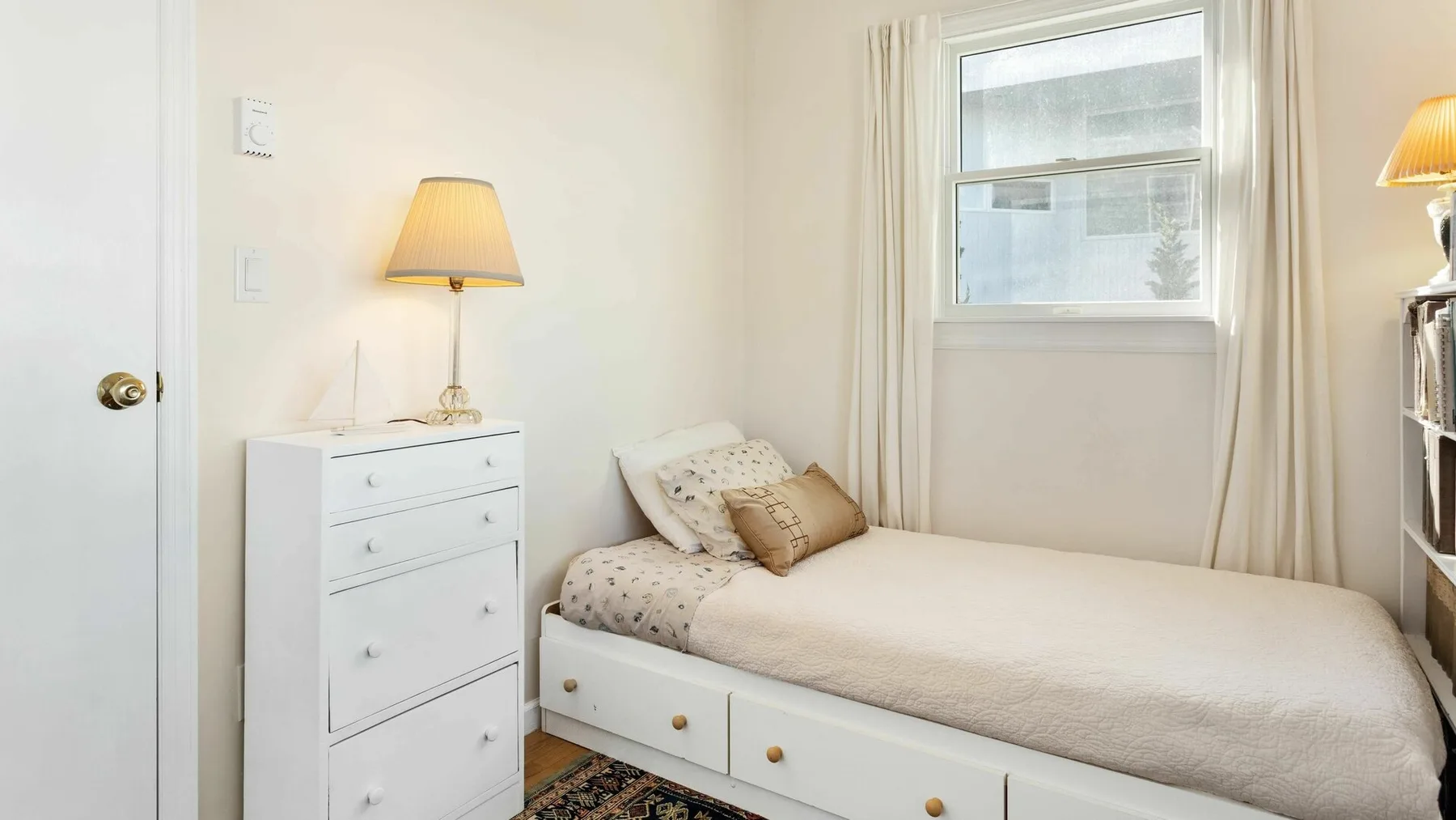 Un dormitorio luminoso con una cama individual y una cómoda blanca.