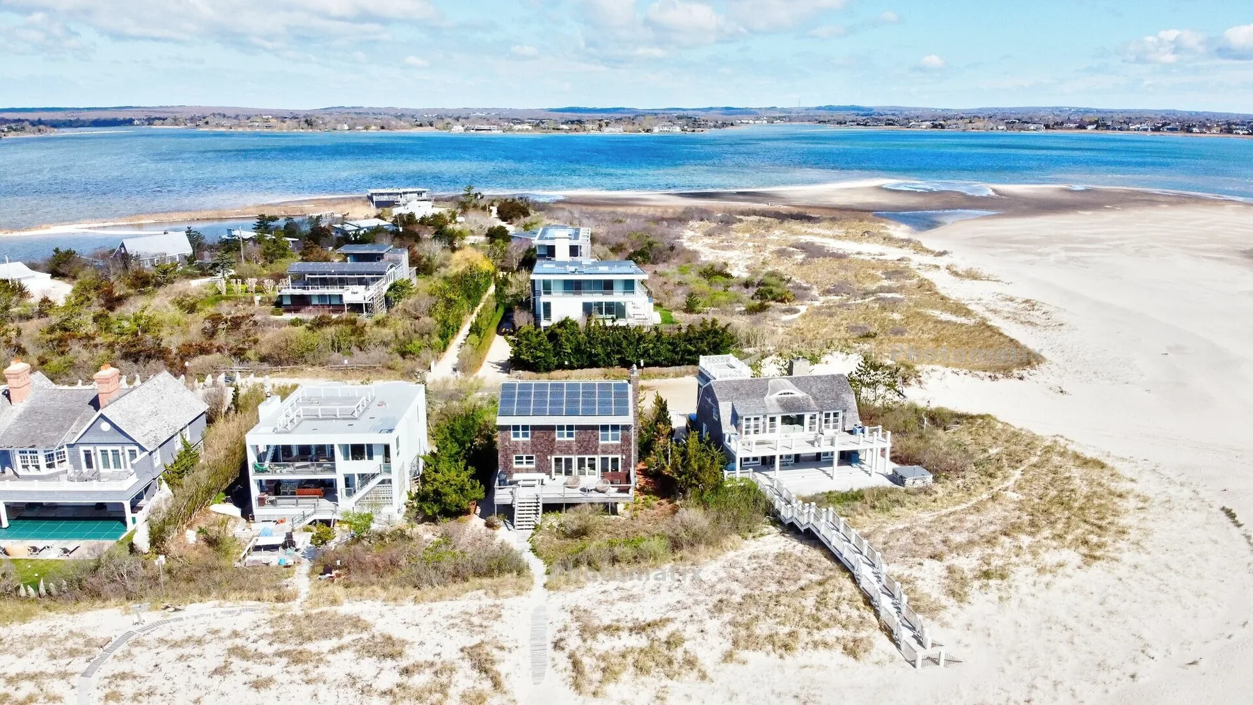 Vista aérea de casas junto a una orilla arenosa y aguas azules.