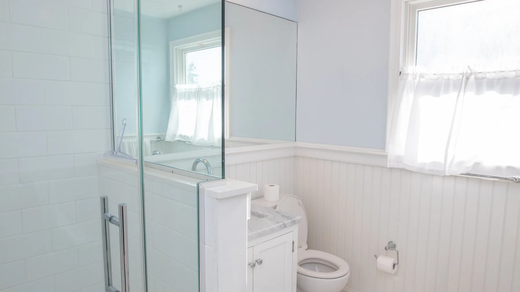 Un baño luminoso con ducha de vidrio, tocador e inodoro.