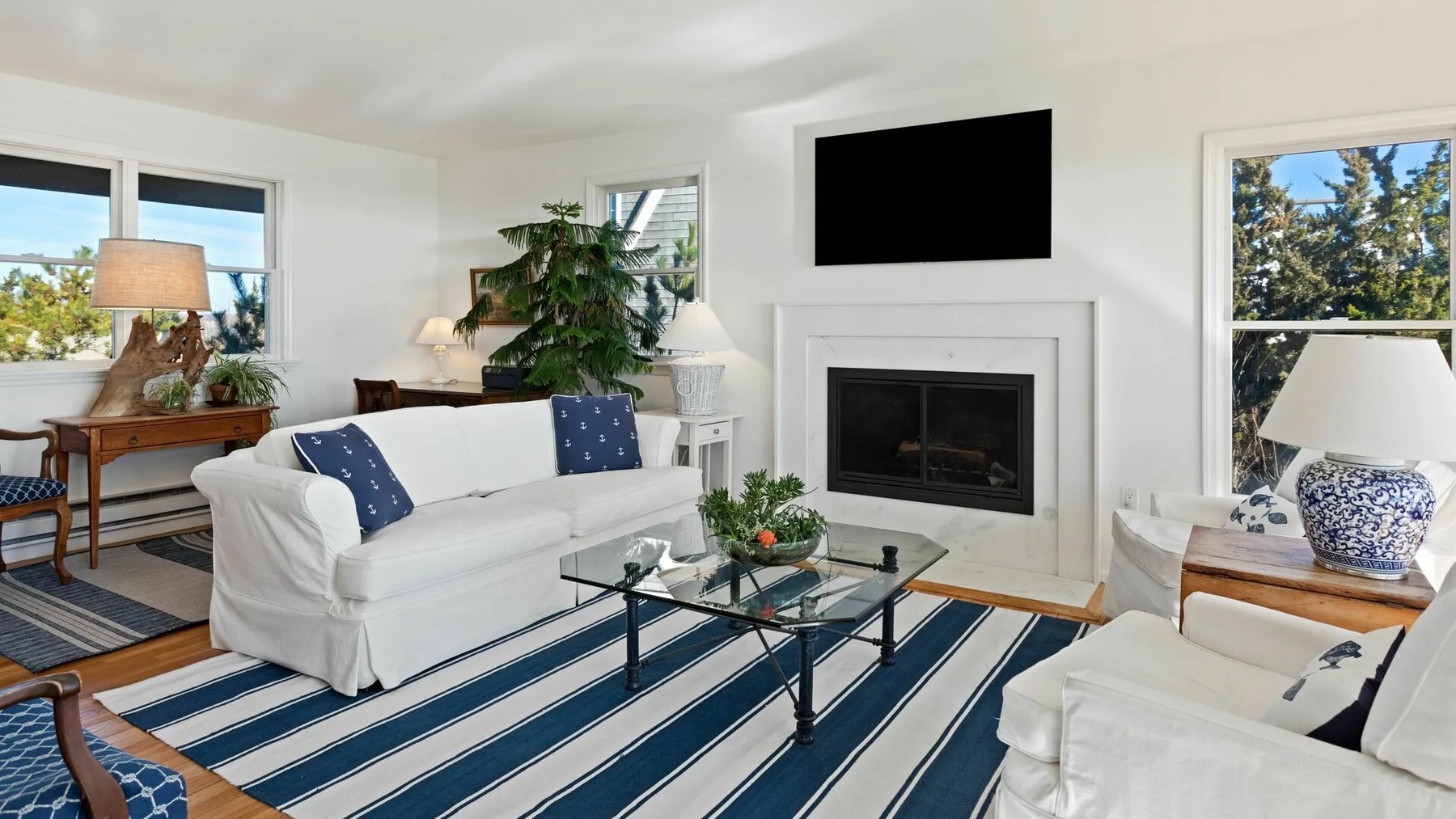 Una sala luminosa con asientos blancos, una chimenea y una alfombra de rayas azules.
