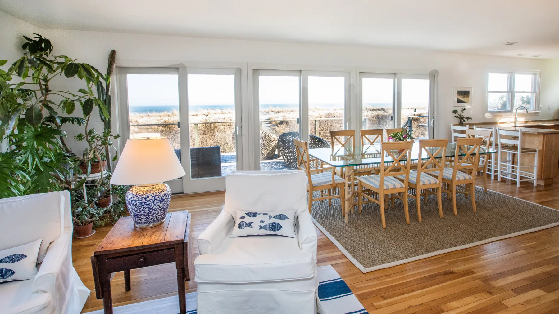 Un luminoso comedor y sala de estar tiene grandes ventanas con vistas a la playa.