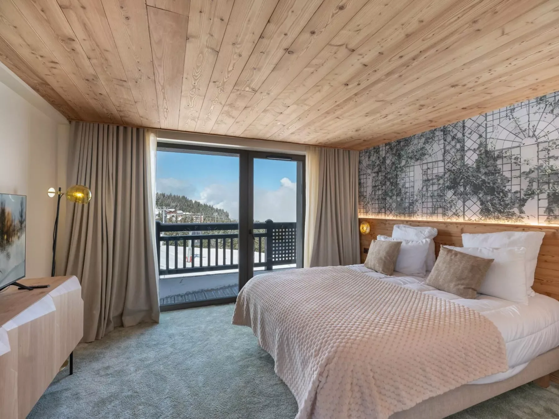 Un dormitorio con una cama grande junto a puertas de vidrio que dan a un balcón.