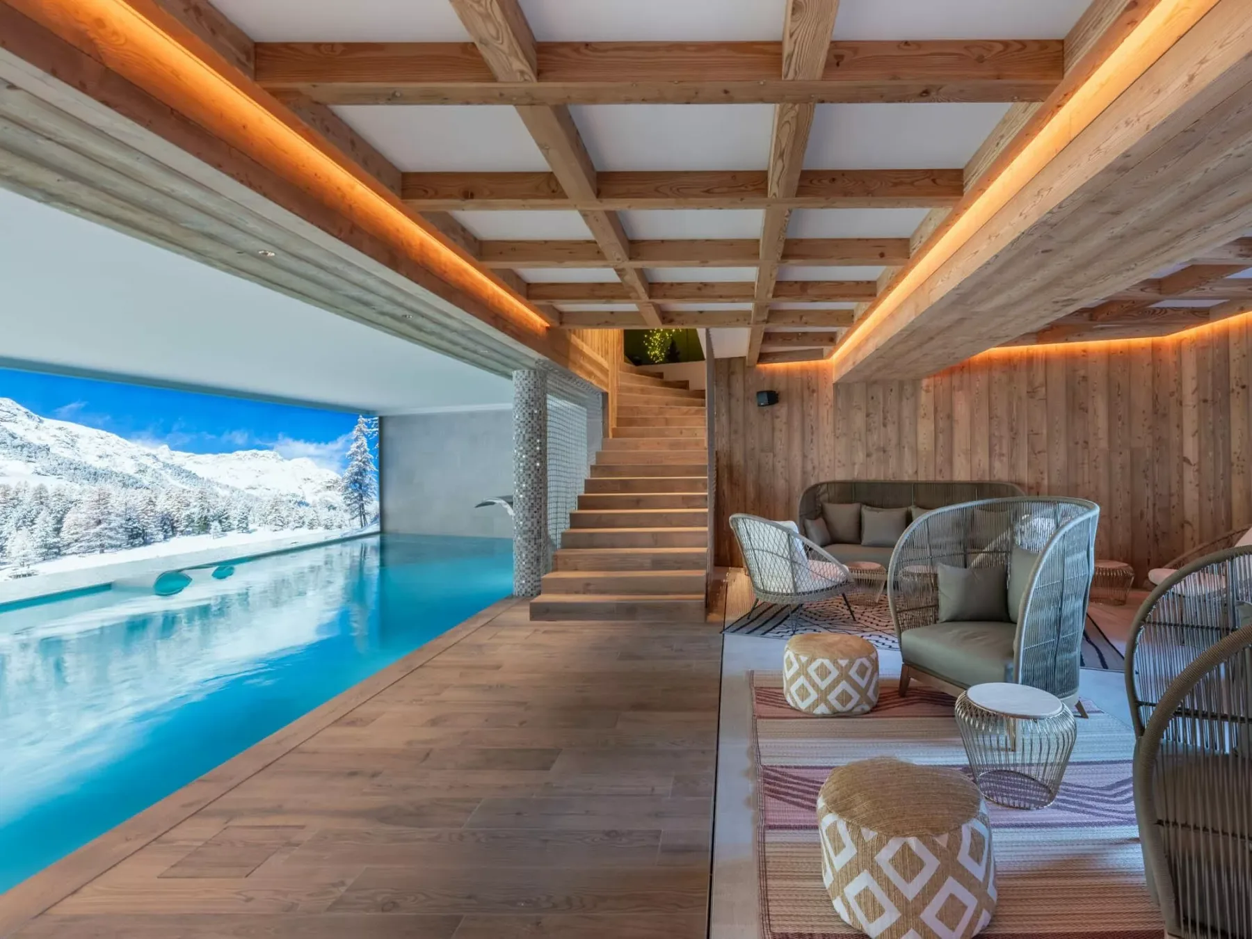 Una piscina interior con suelo de madera y asientos junto al agua y una ventana grande.