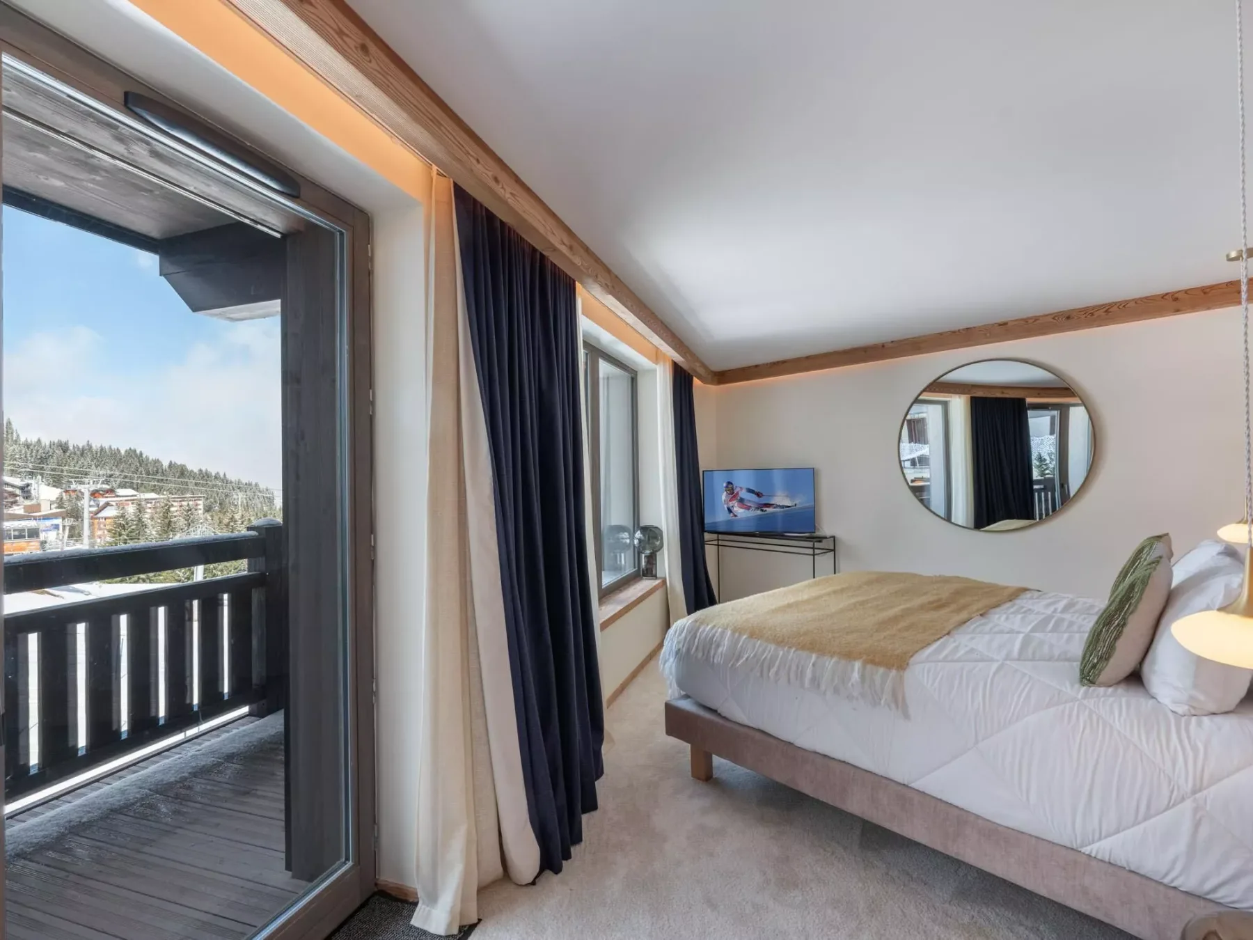 Un dormitorio con una cama, un televisor y puertas de vidrio que dan a un balcón.