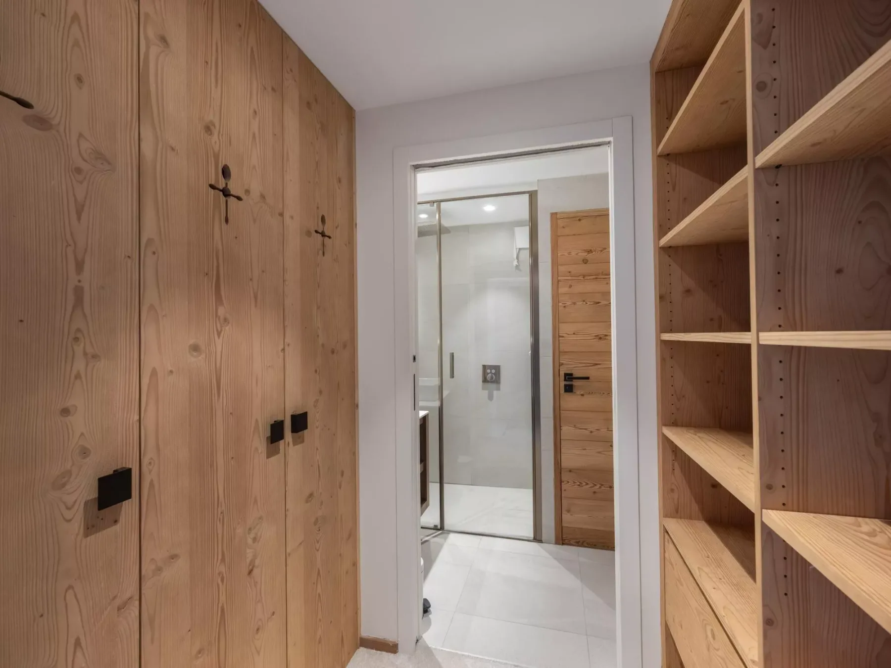 Un vestidor revestido de madera da a un baño luminoso.