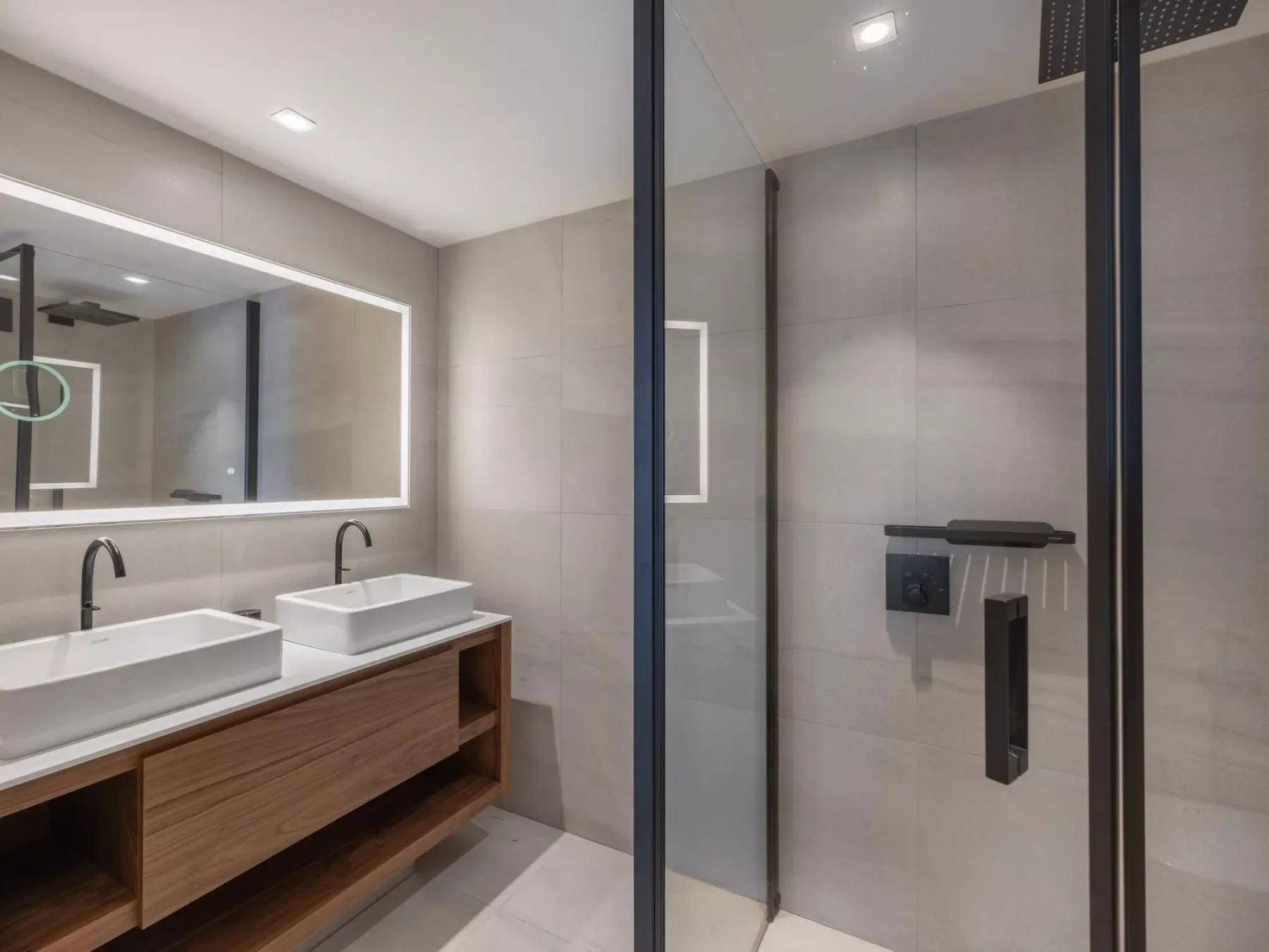 Un baño moderno con lavabo doble y ducha con mampara de vidrio.