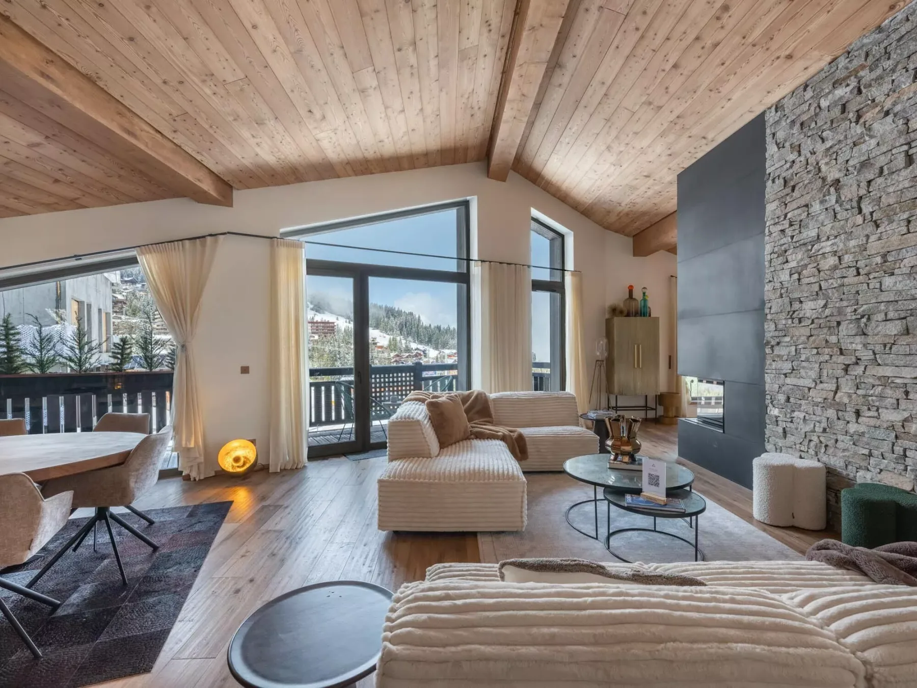Una sala luminosa con asientos junto a grandes ventanales con vistas a un paisaje boscoso.