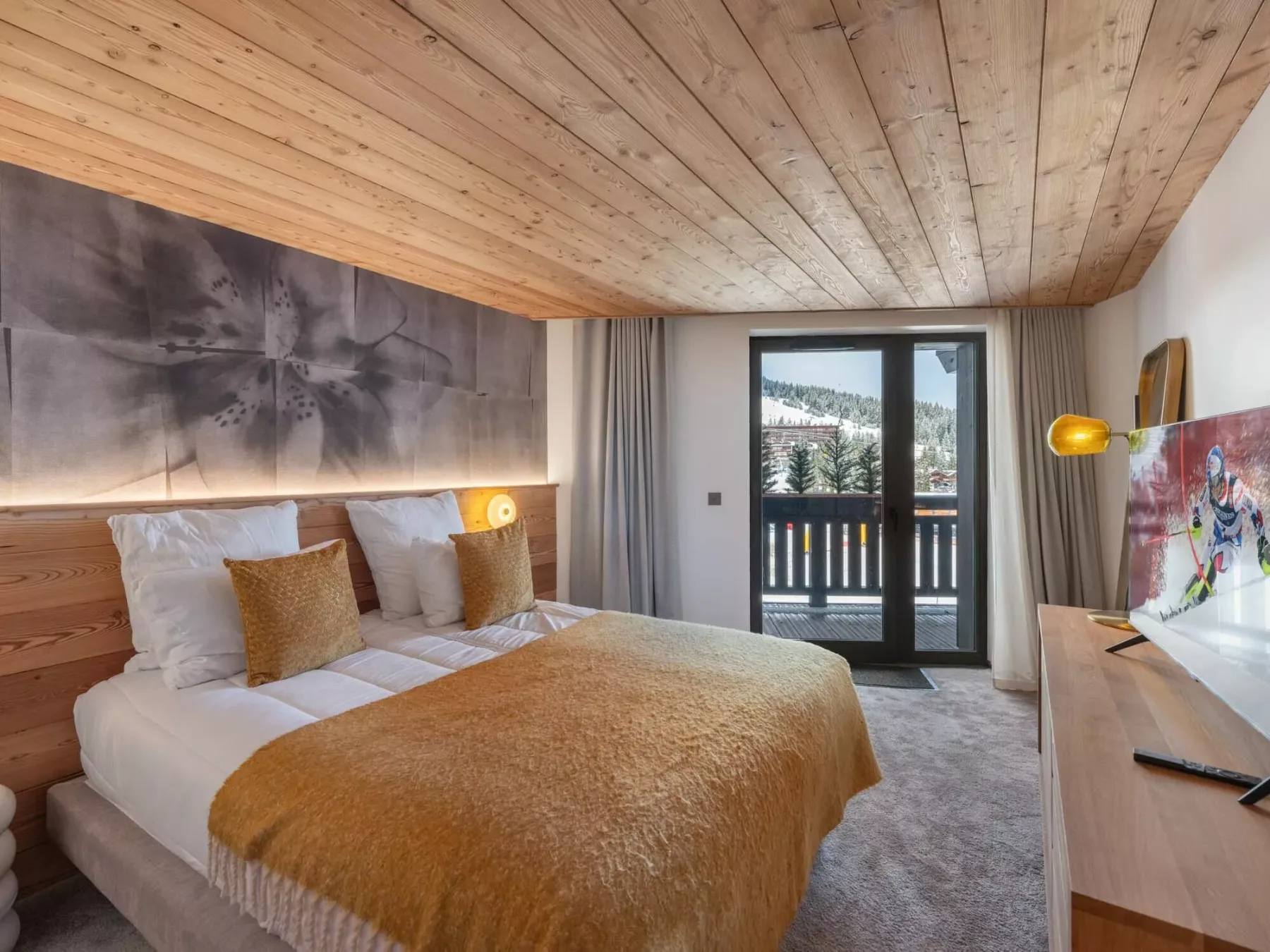Un dormitorio con una cama, techo de madera cálida y puertas de vidrio que dan a un balcón.
