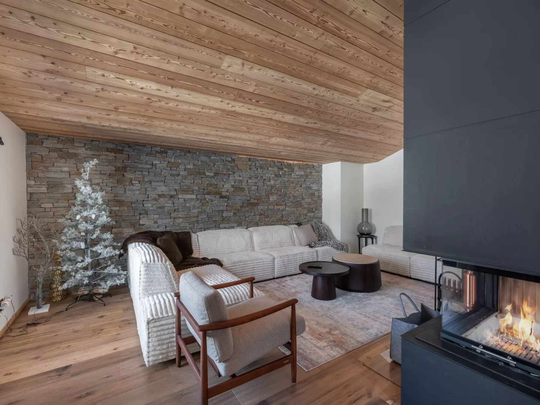 Una sala de estar con asientos junto a una chimenea bajo un techo inclinado de madera.