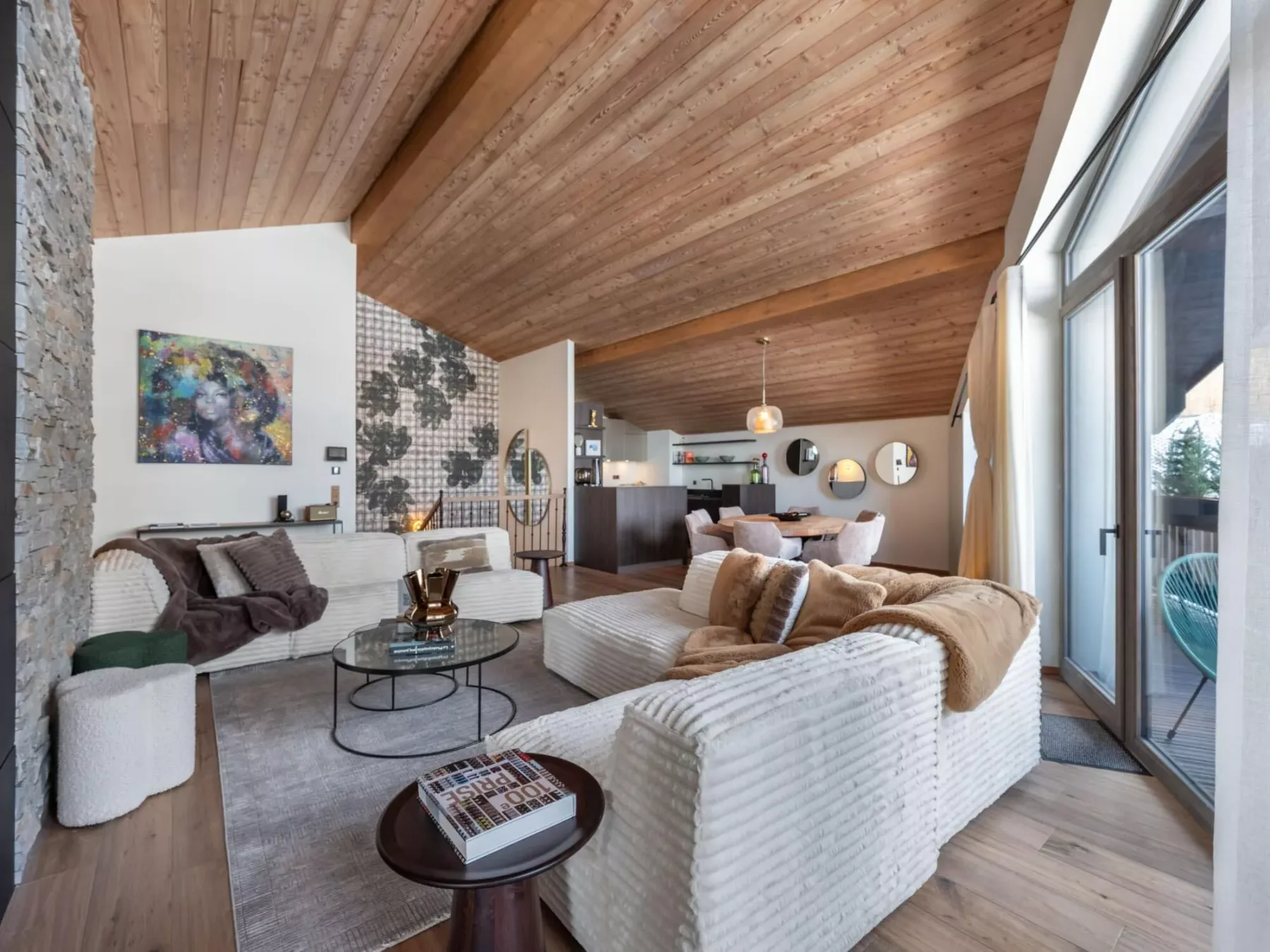 A spacious living room with seating arranged around low coffee tables and large windows.