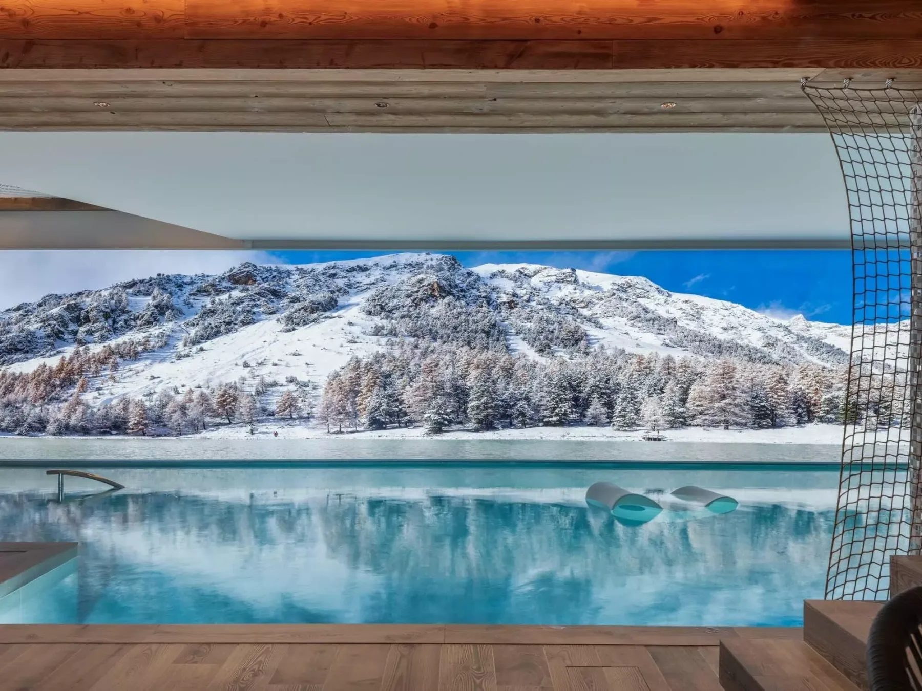 Una piscina mira hacia una montaña nevada bajo un cielo azul despejado.