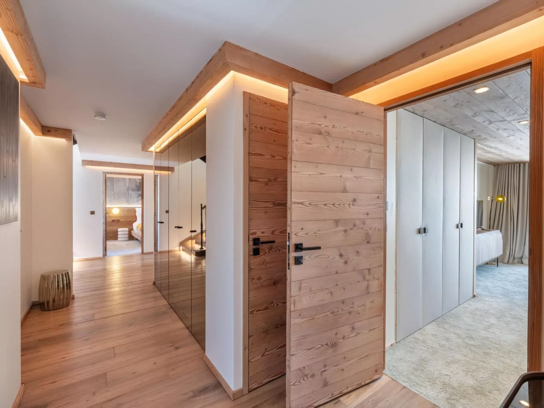 La entrada de madera de un dormitorio da a una habitación luminosa con suelo claro.