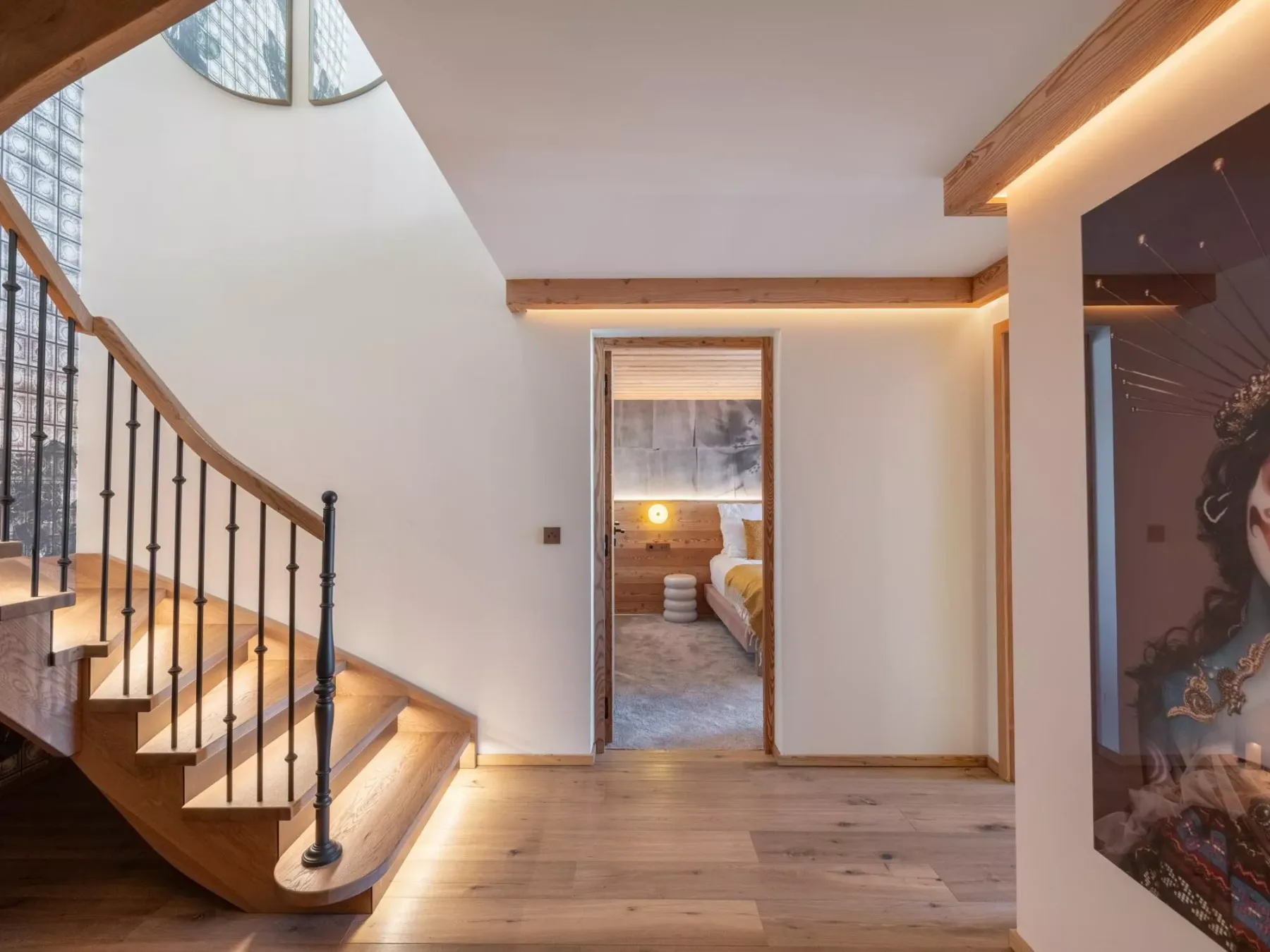 Un pasillo interior con una escalera y un dormitorio visible a través de la puerta.
