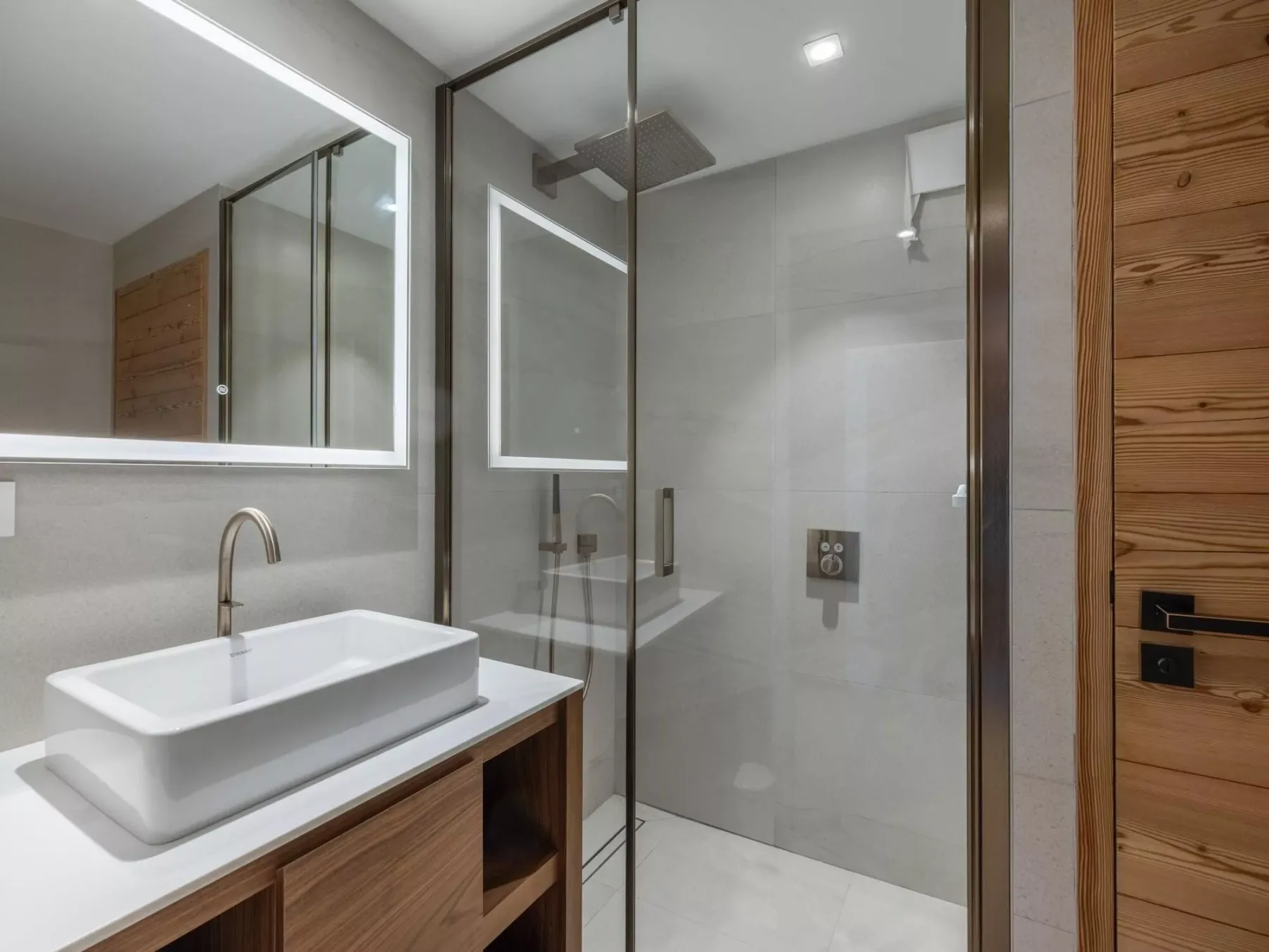 Un baño moderno con un lavabo sobre encimera junto a una ducha de vidrio.