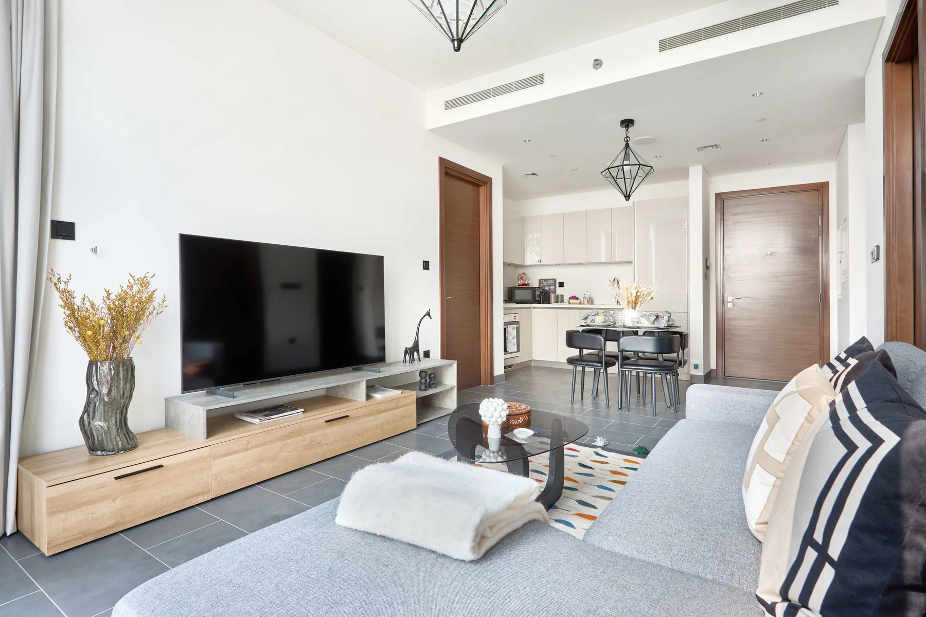 Una luminosa sala de estar con televisor, asientos y una cocina-comedor abierta.