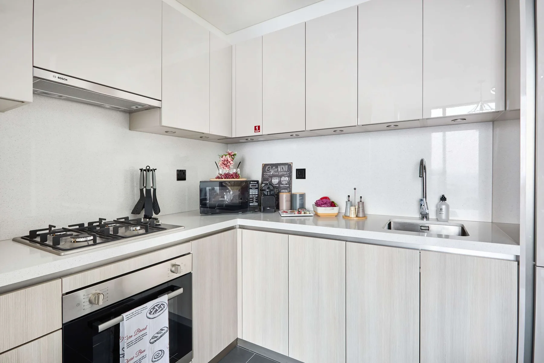 Una cocina moderna y luminosa con gabinetes blancos, una placa de cocina y un fregadero.