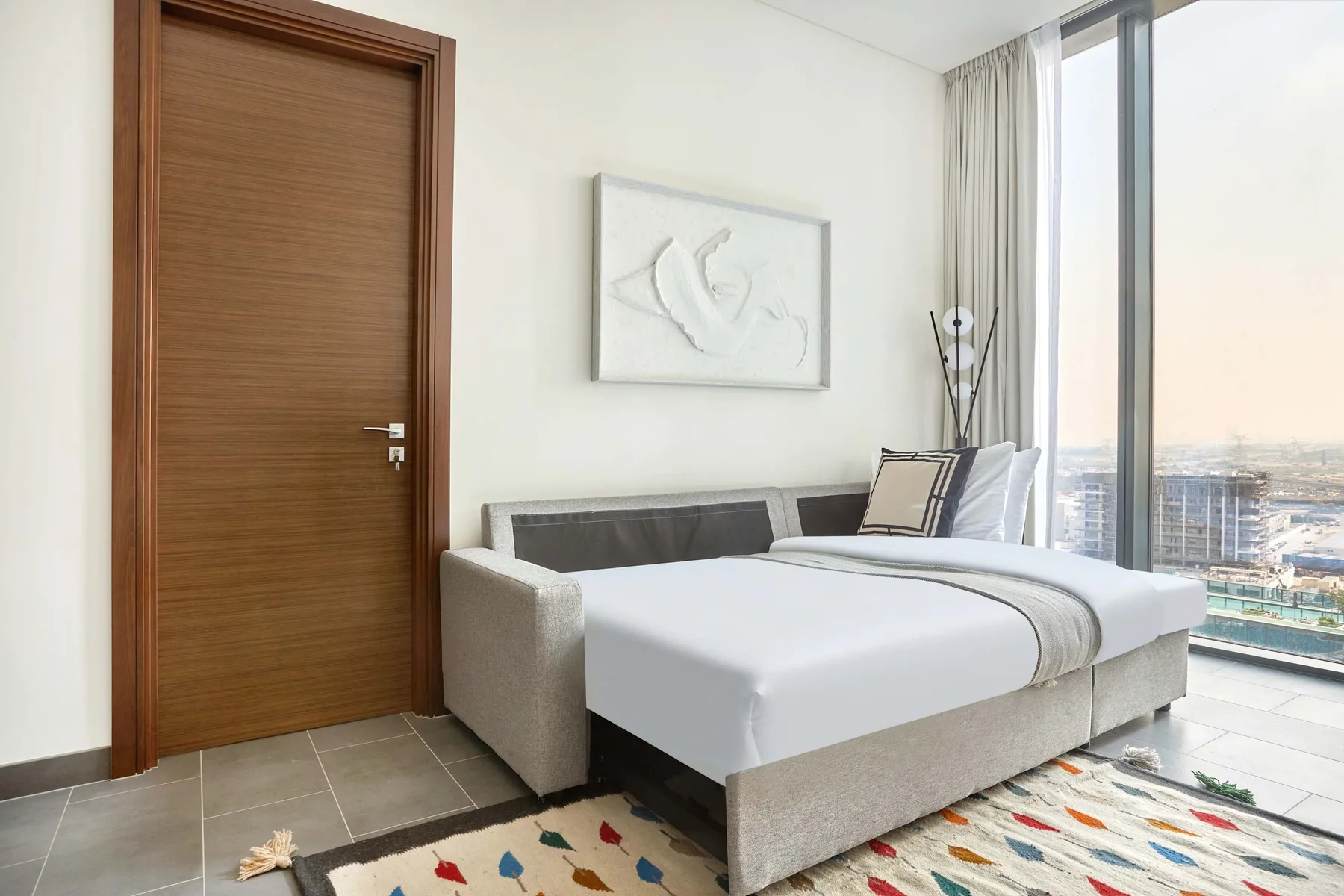 Un dormitorio luminoso con una cama bien arreglada junto a una ventana grande.